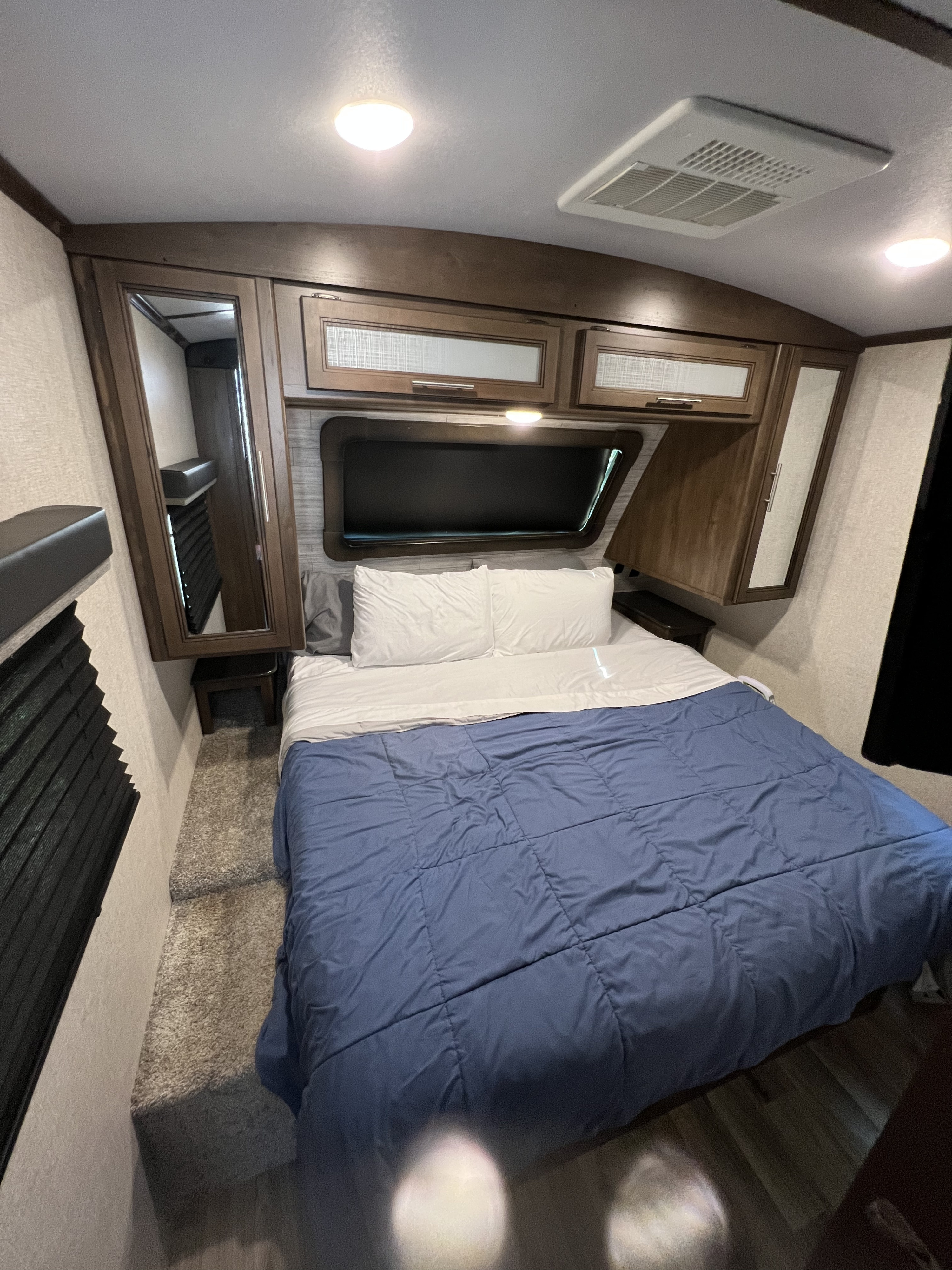 Experience comfort in this RV rental bedroom. Features include a bed, overhead cabinets, air conditioning, and a mirror.. Keystone Cougar Half-Ton 2021