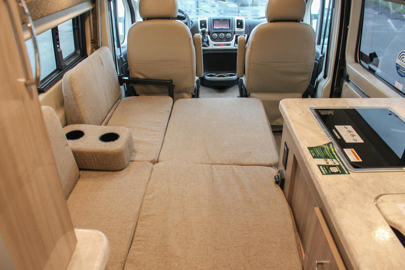 RV rental interior: front cabin, versatile seating converting to a bed, and kitchen with cooktop. Perfect for road trips.. Thor Scope 2022