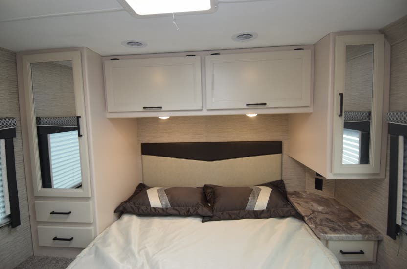 Experience comfort in this RV rental bedroom with a bed, mirrored wardrobes, overhead cabinets, and a nightstand for your travels.. Thor Motor Coach Chateau 2022