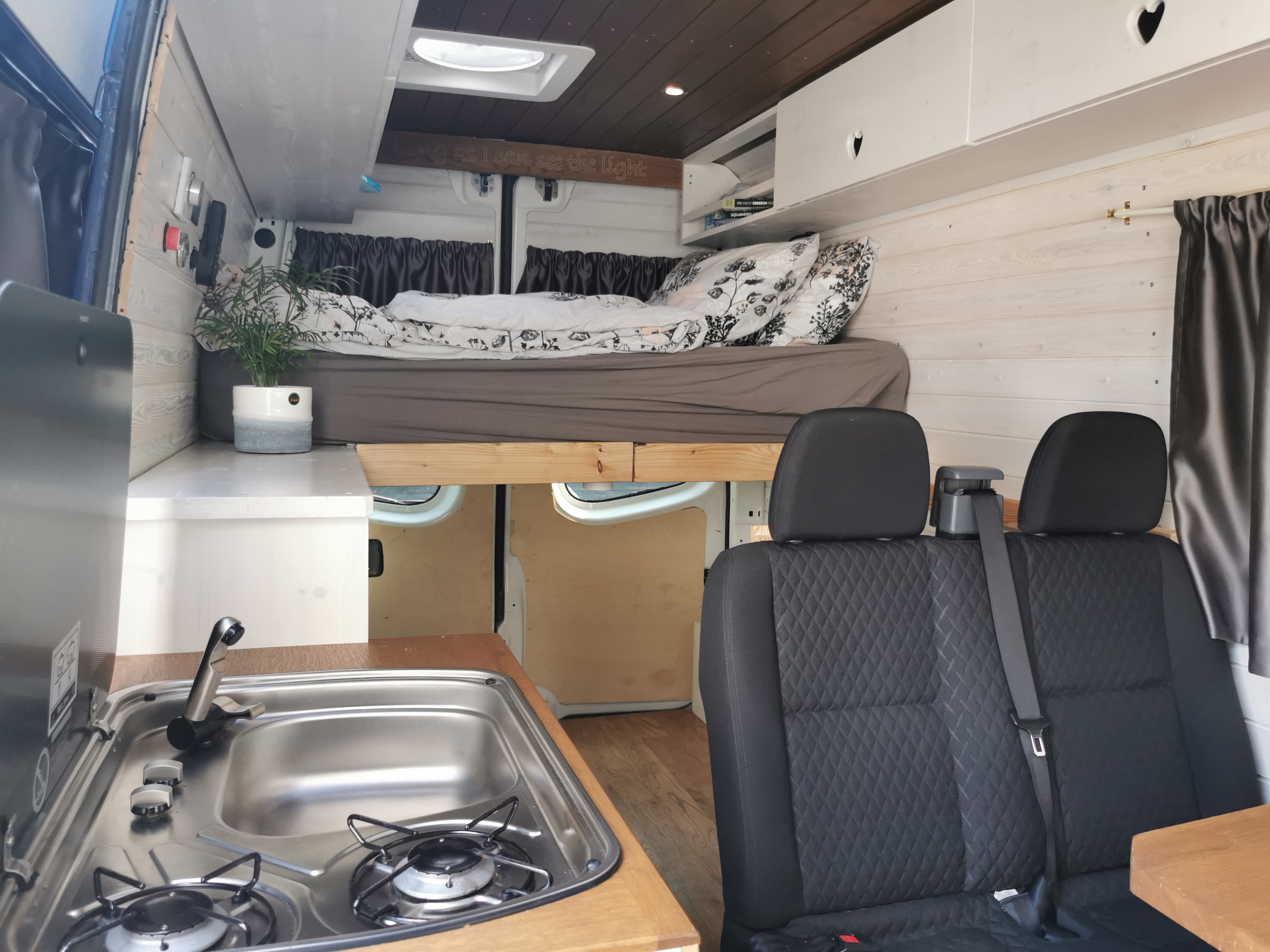 Cozy campervan RV rental interior: bed, kitchen area, and seats create a functional living space.. Leisure Travel Vans Leisure Travel Vans Class B 2006