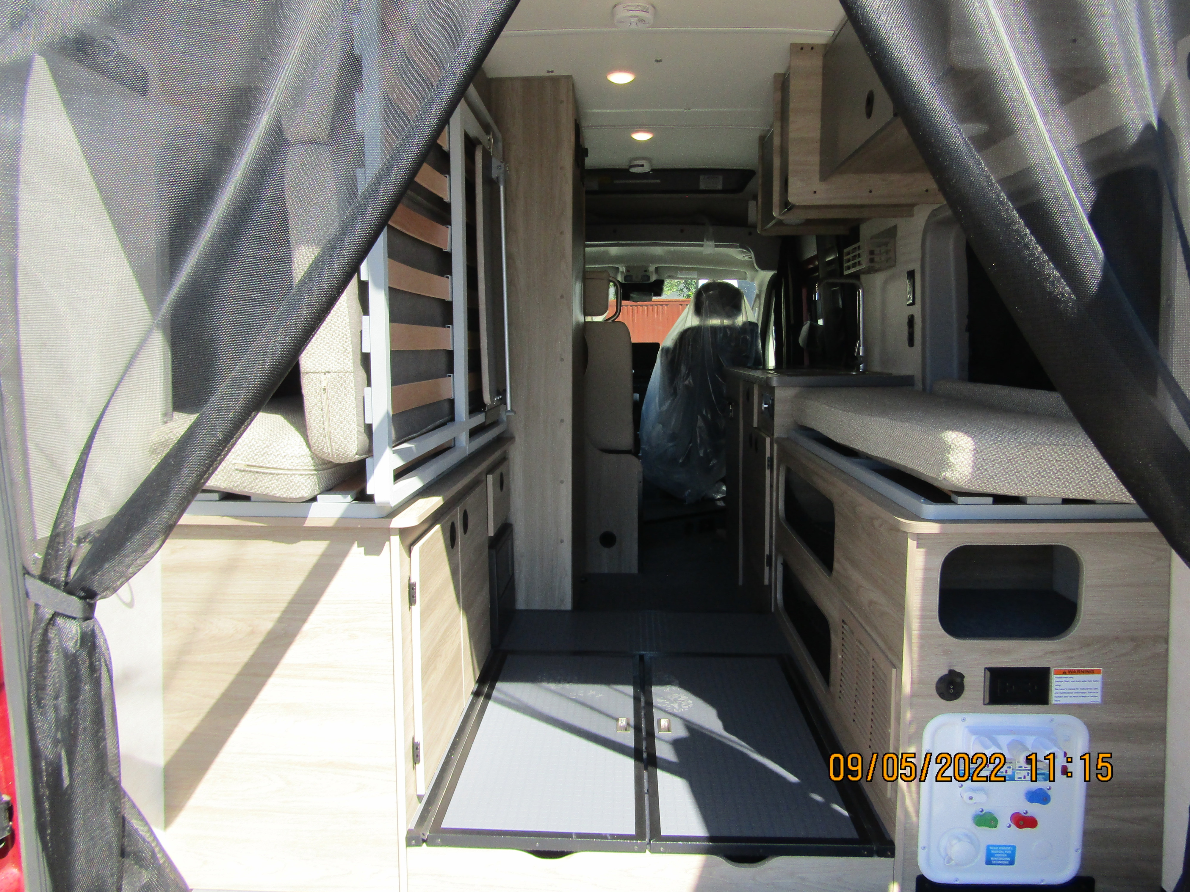 Interior view of a modern RV rental, showing compact living space, convertible bed, and control panel.. Winnebago SOLIS 2023