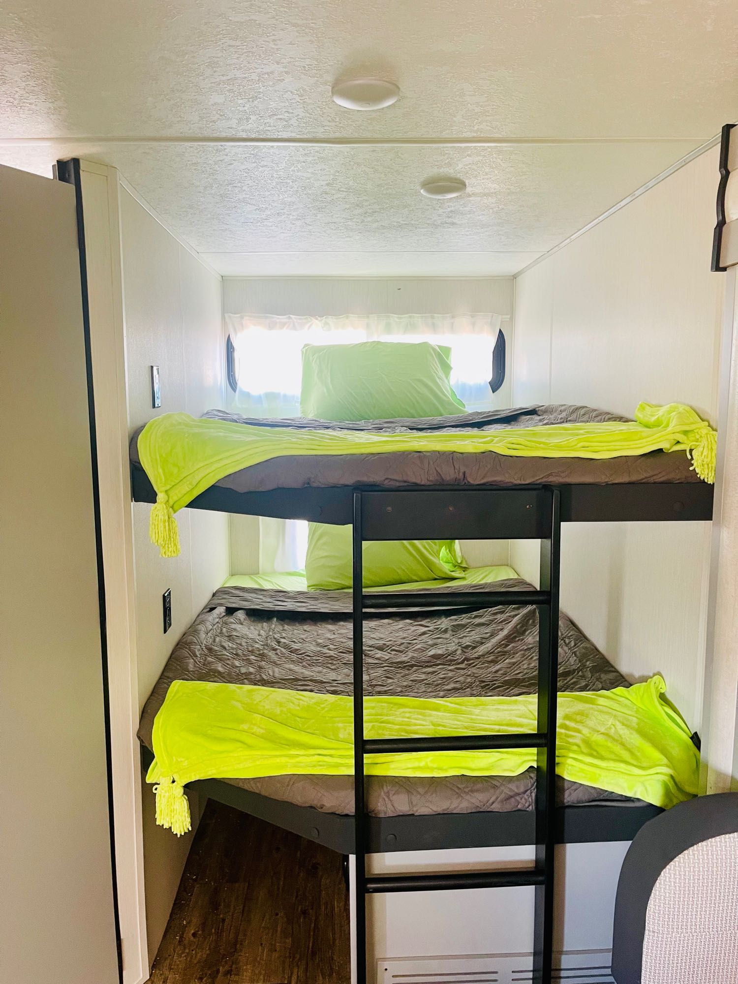 Cozy RV rental interior showing two bunk beds with bright green and gray bedding, ideal for family trips.. Forest River Vibe 2022