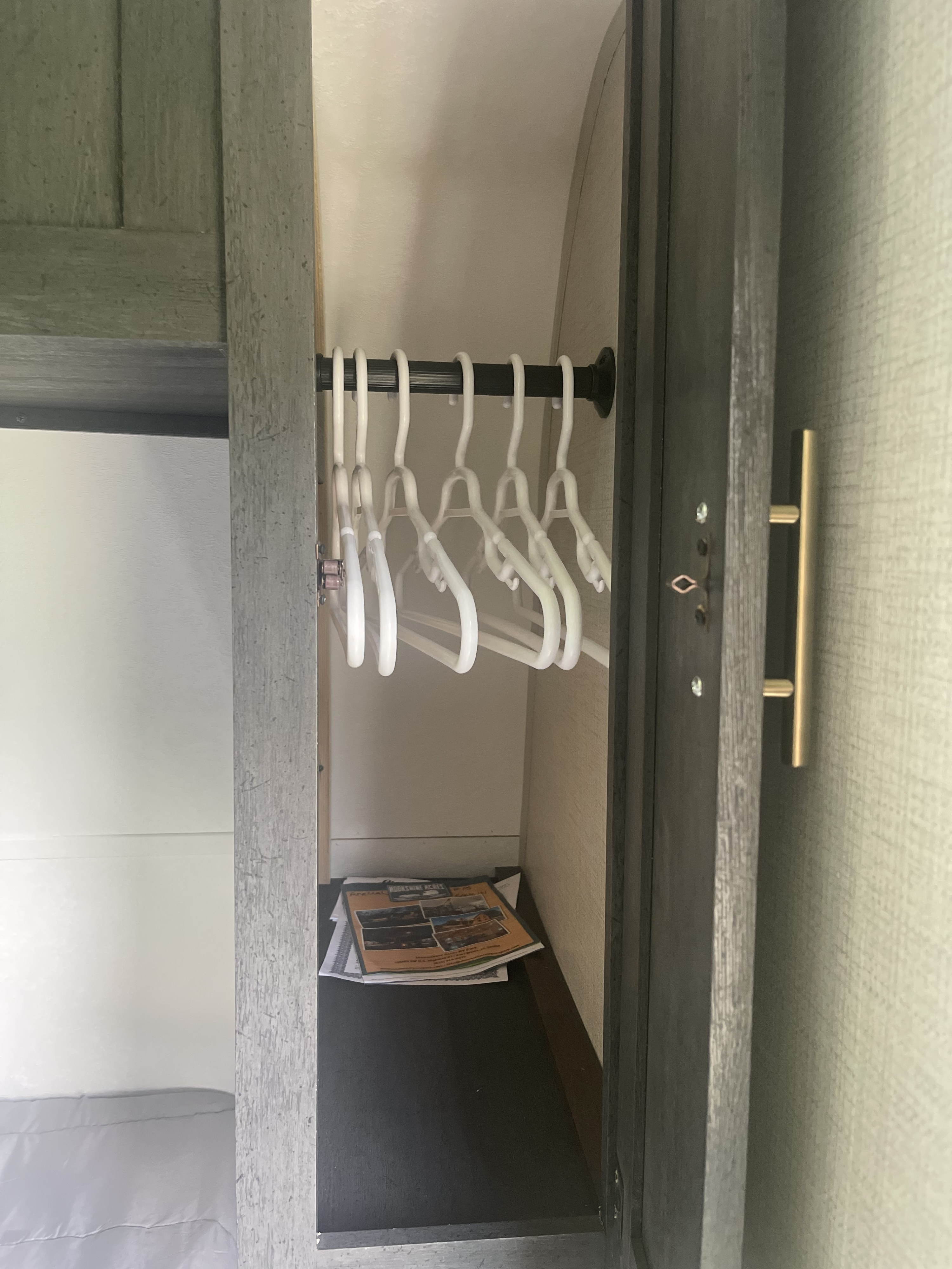 RV rental interior showing a compact wardrobe with white hangers and lower storage.. Forest River Ozark 2022