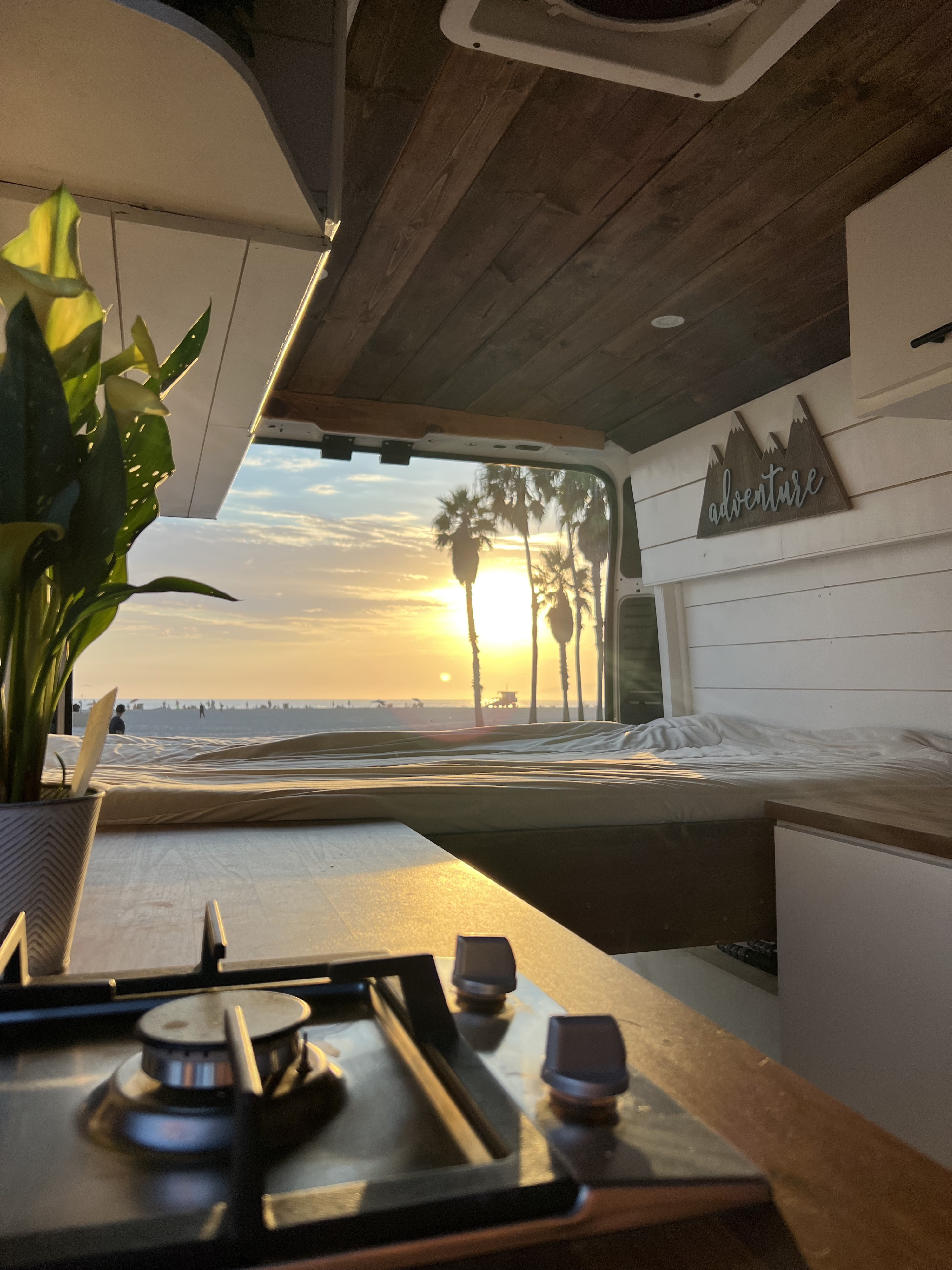 Cozy RV rental with stunning sunset beach views. Features a bed, kitchen, and 'adventure' sign for your travels.. Dodge Other 2021
