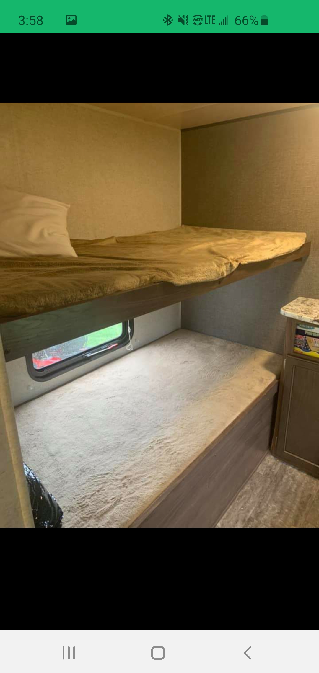 RV rental bunk beds. Inside a cozy travel trailer, showing upper and lower bunks with bedding and a window.. Heartland RVs Trail Runner SLE 2018