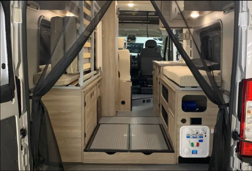 View inside an RV rental from the rear, showing sleeping areas, storage cabinets, and a central aisle leading to the front.. Winnebago Solis 2021