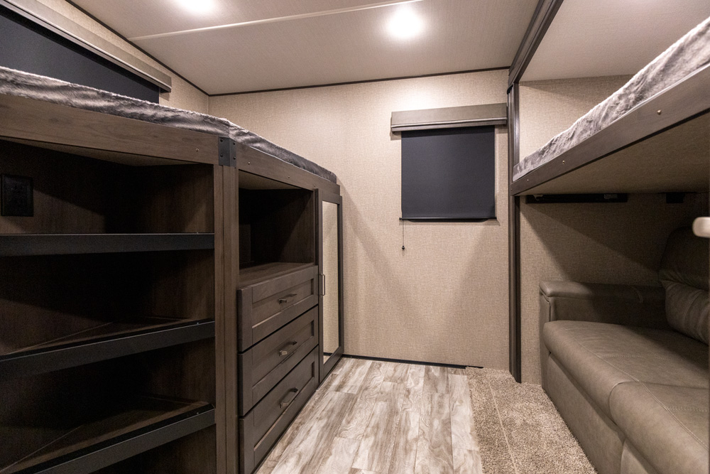 RV rental bunkhouse features: built-in storage, dresser, window, and a sofa under upper bunks. Ideal for family travel.. Grand Design Reflection 2021
