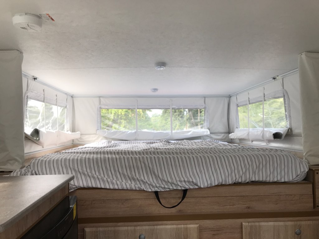 RV rental: Bright, spacious pop-up camper bed with striped bedding and large windows. Ideal for travel.. Northstar Truck Camper Tc650 2021