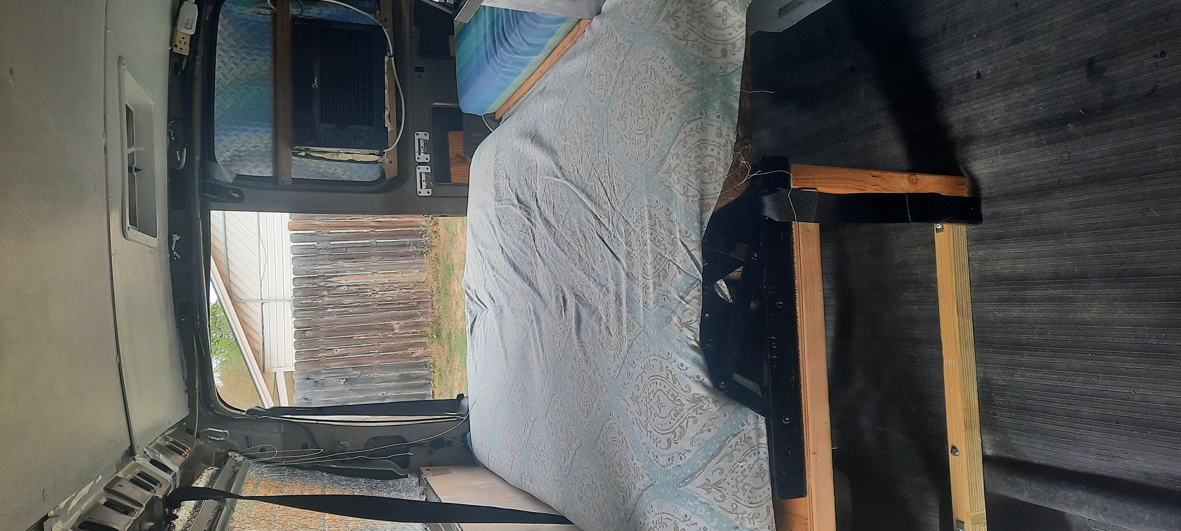 RV rental ready: Cozy camper van interior with a bed, window view, and portable A/C for mobile comfort.. Chevrolet Express 2011