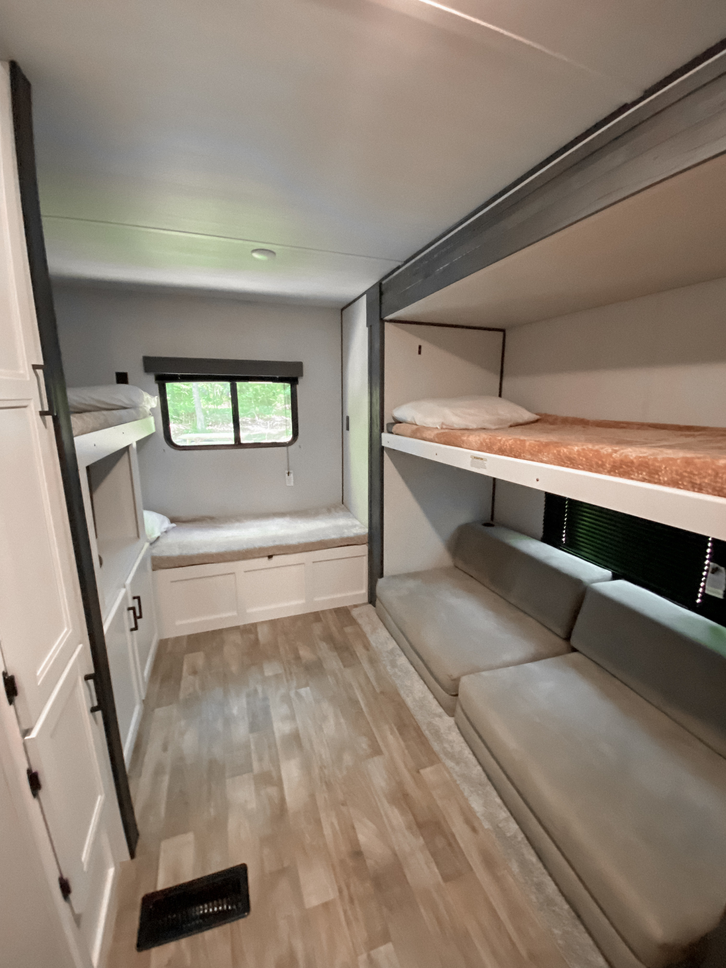 RV rental interior: Cozy bunk beds and spacious seating area for your travels, featuring light wood flooring.. Keystone RV Hideout 2022