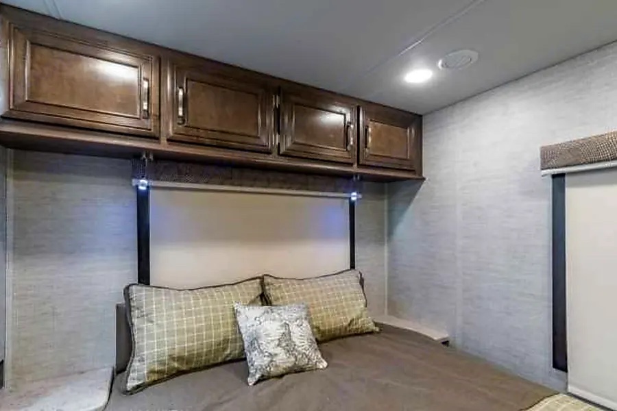 RV rental: a cozy bedroom with a comfortable bed, overhead cabinets, and integrated headboard lighting.. Entegra Coach Esteem 2021