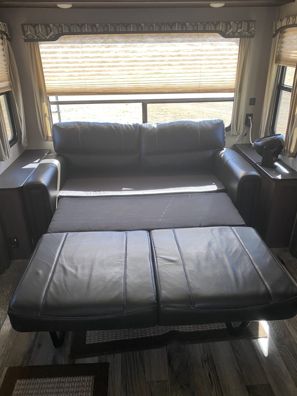 RV rental: Dark leather sofa bed extended for sleeping, with end tables & bright window. Ideal RV living space.. Keystone Hideout 2019