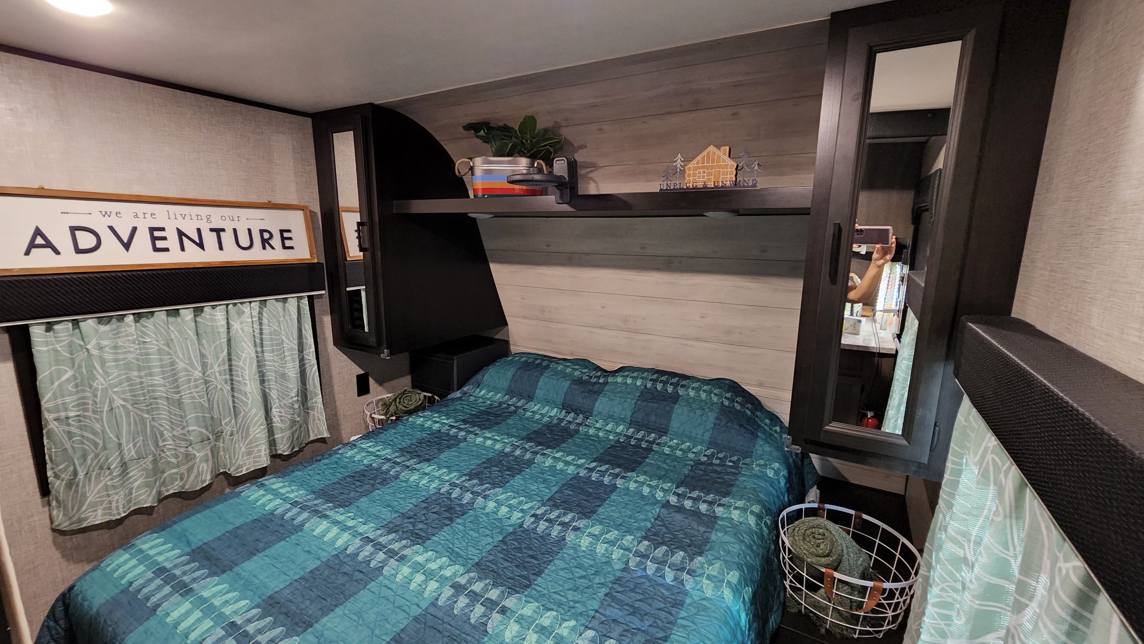 Cozy RV rental bedroom featuring a blue quilt, "ADVENTURE" sign, and built-in storage for comfortable travels.. Jayco Jay Flight SLX 2022