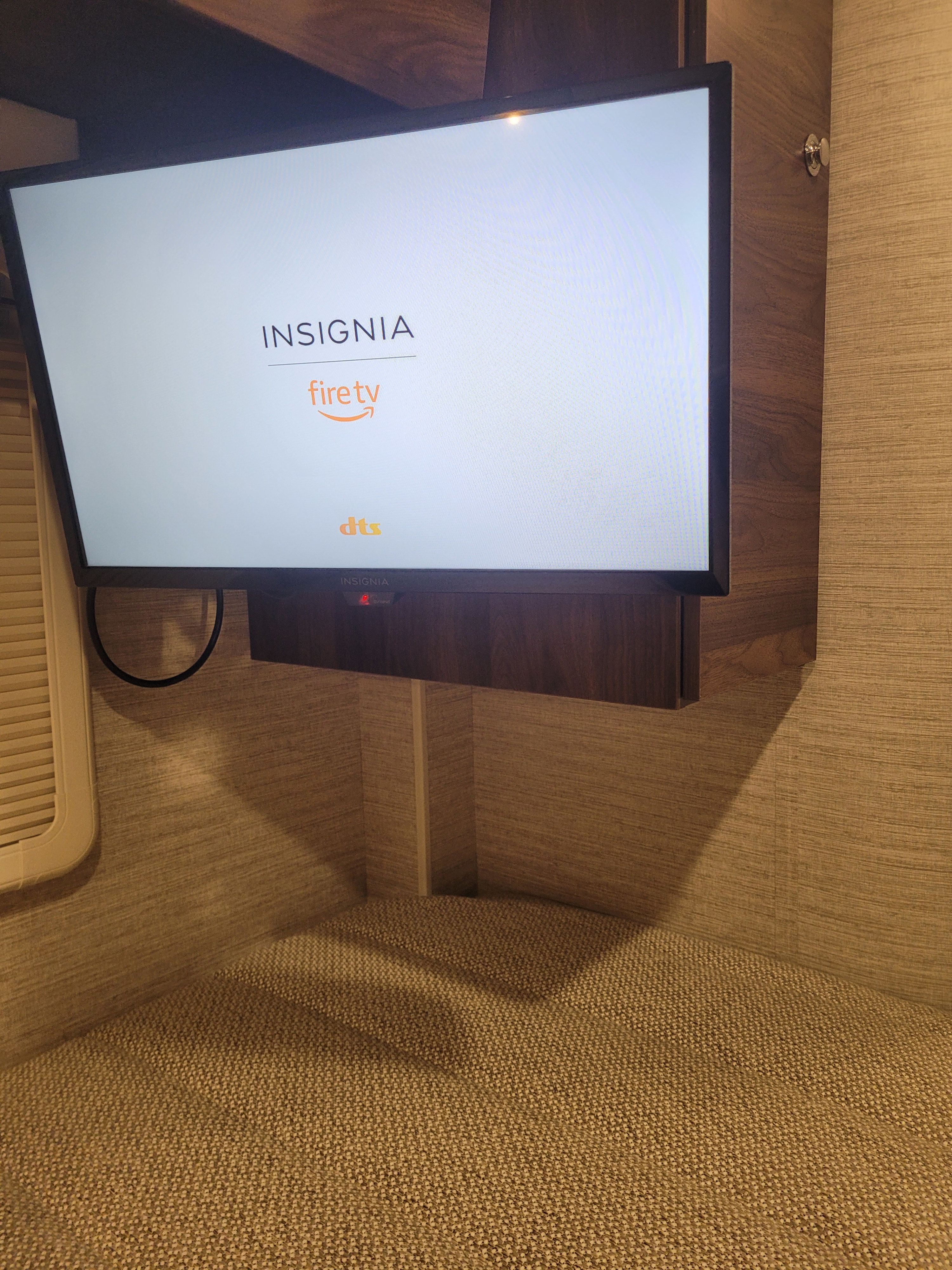An Insignia Fire TV, displaying its boot screen, is mounted in a modern RV rental's cozy interior, ready for entertainment.. Winnebago View 2023