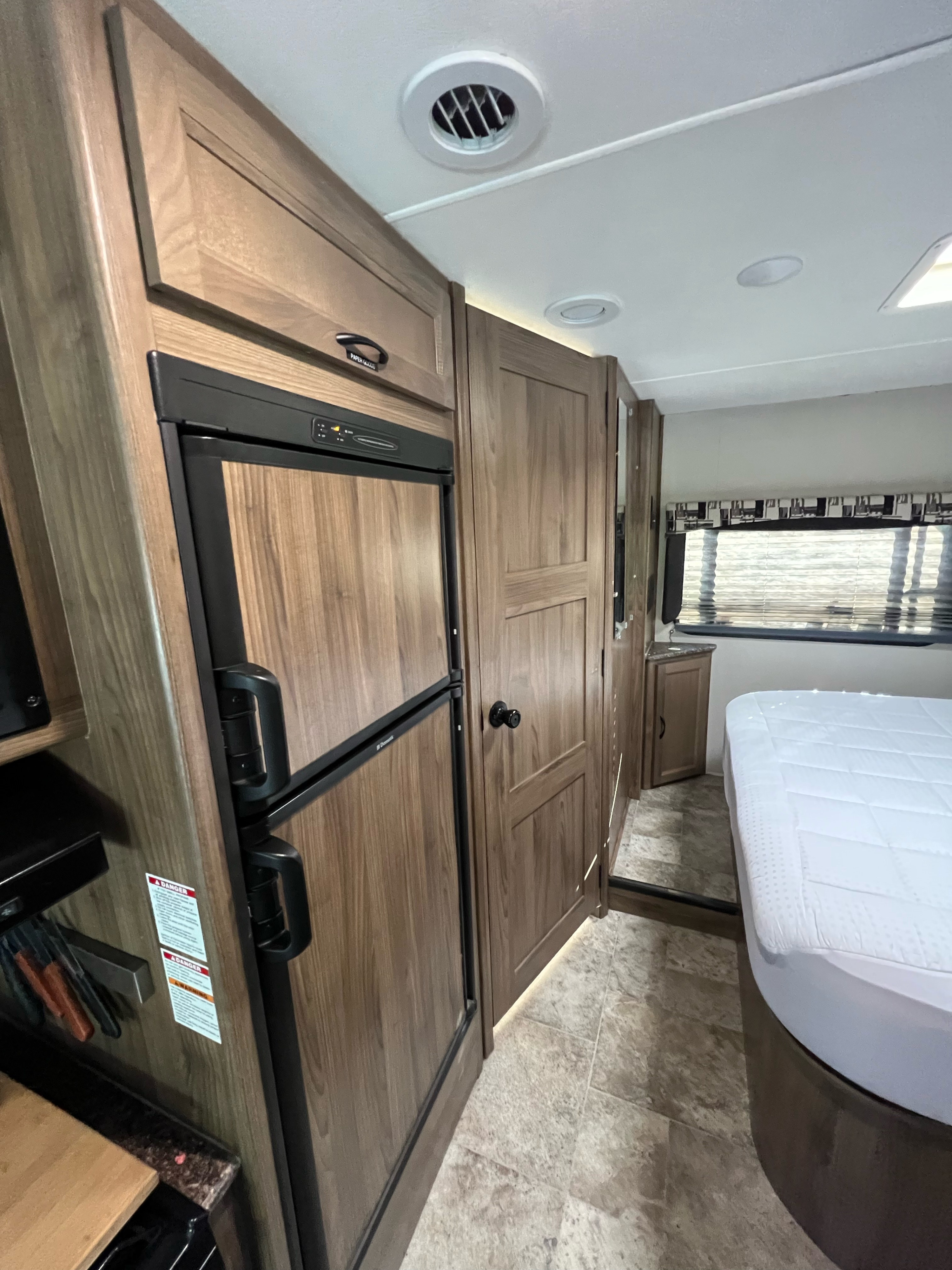 This RV rental's interior features a refrigerator, wood-toned cabinets, and a comfortable bedroom area.. Forester GTS 2017