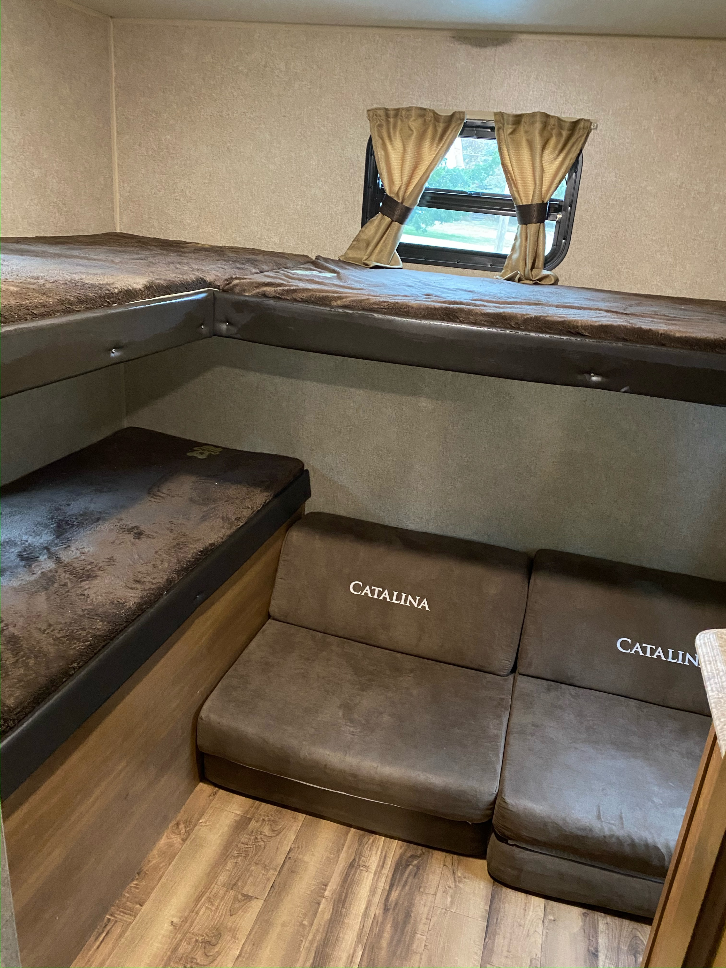 Cozy RV rental interior showcasing brown bunk beds, a lower 'Catalina' sofa, and a small window with curtains.. Coachmen 5ZT2CAUB5JU029455 2018