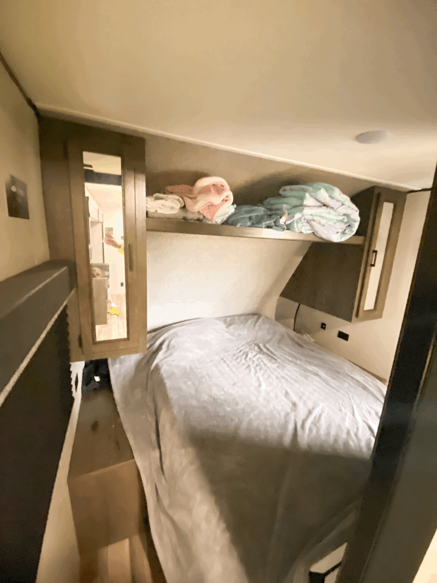This RV rental bedroom offers a cozy bed, overhead shelf with blankets, and built-in storage cabinets.. Starcraft Autumn Ridge 2022