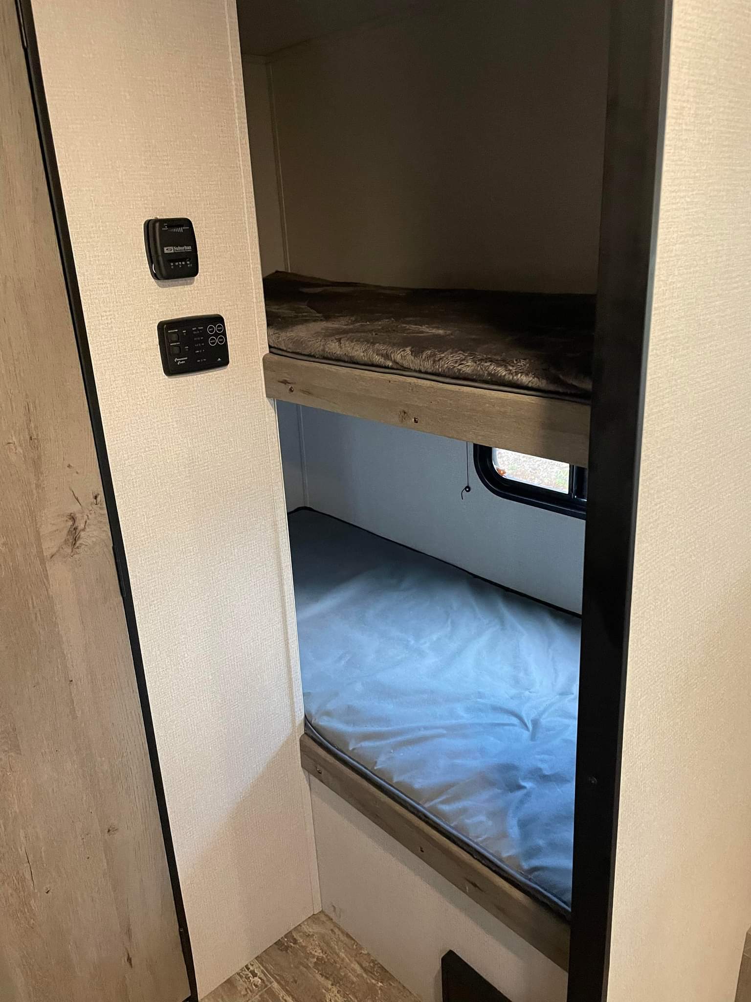 Inside an RV rental, showing compact bunk beds and wall-mounted controls for comfort and utilities.. Keystone RV Springdale 2021