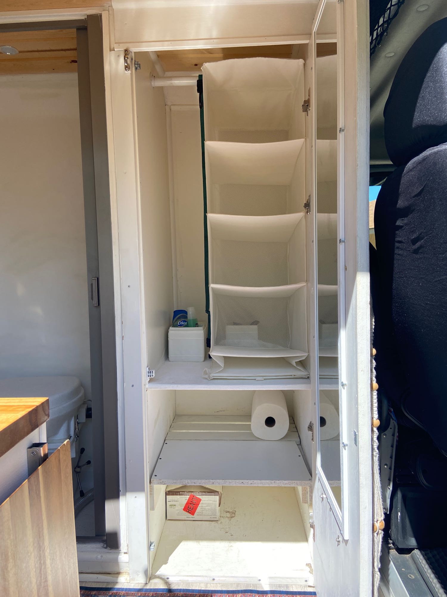 RV rental interior: A compact closet with hanging storage, toilet paper, and a nearby toilet, maximizing space.. Dodge Ram Promaster 2500 2017