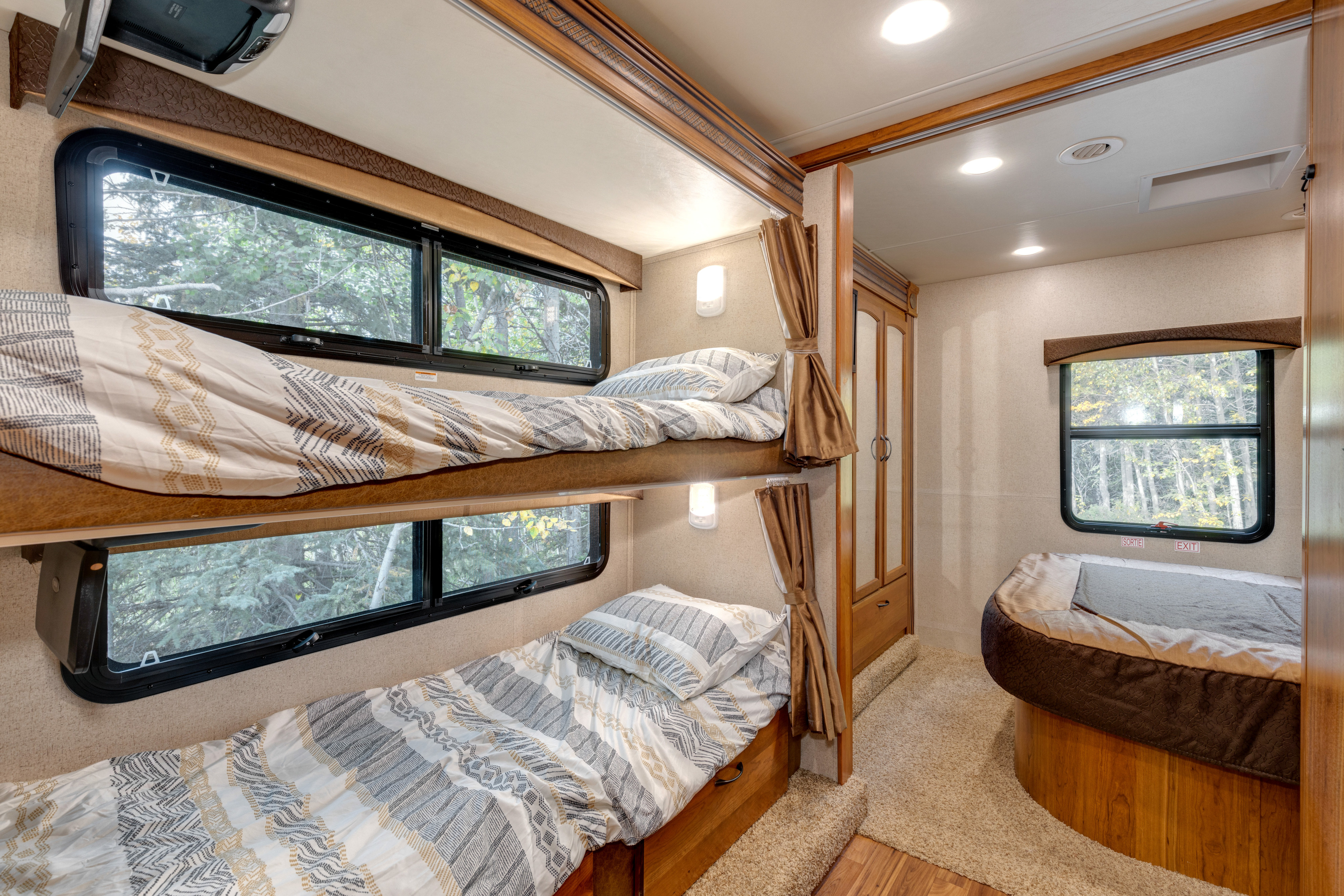 Spacious RV rental interior featuring cozy bunk beds, a main bed, and scenic window views of nature.. Jayco Greyhawk 2016