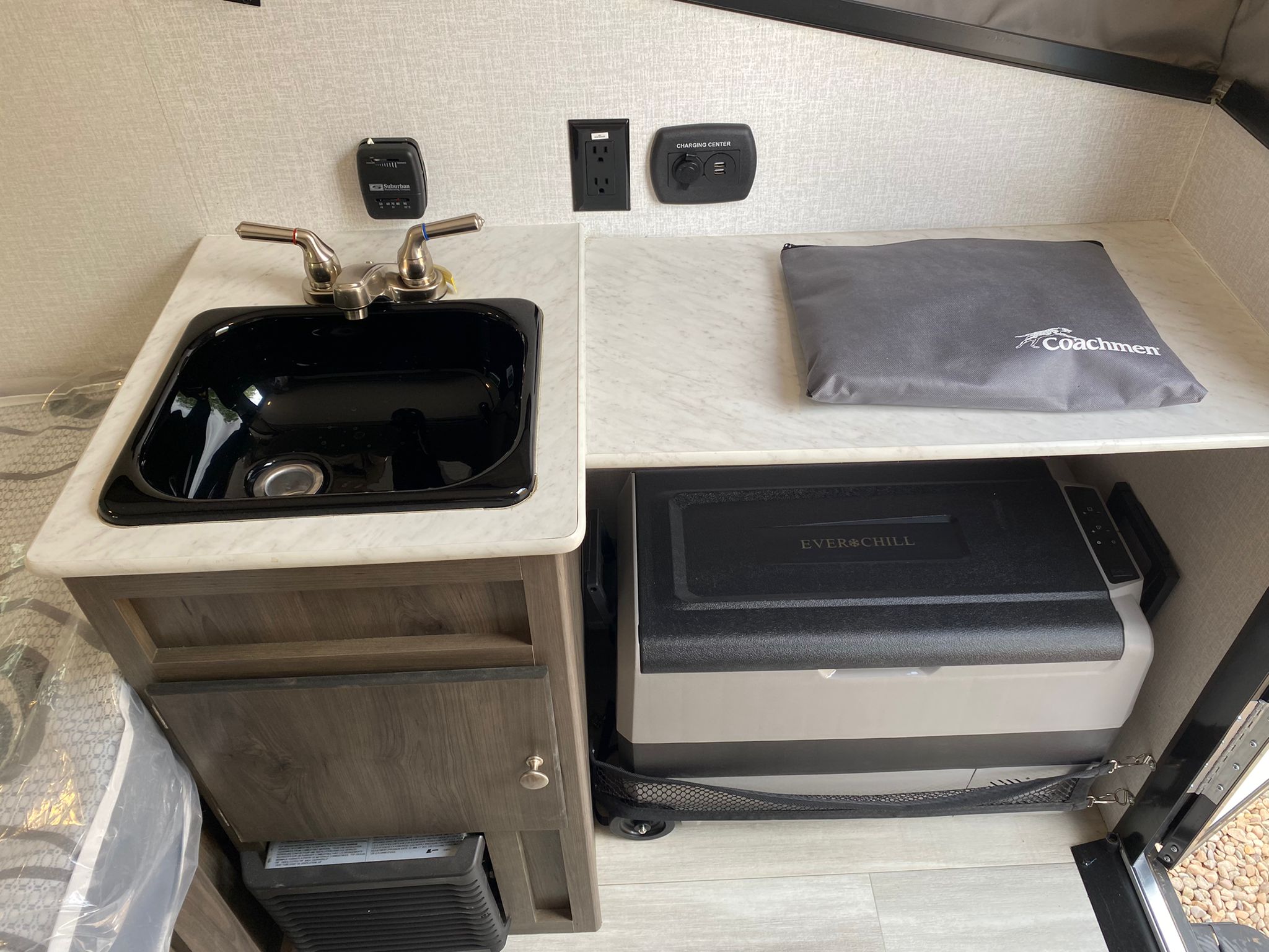 Compact RV rental kitchen area showing a sink, faucet, power outlets, and a pull-out Ever Chill cooler.. Coachmen Clipper Express 9.0 TD 2022