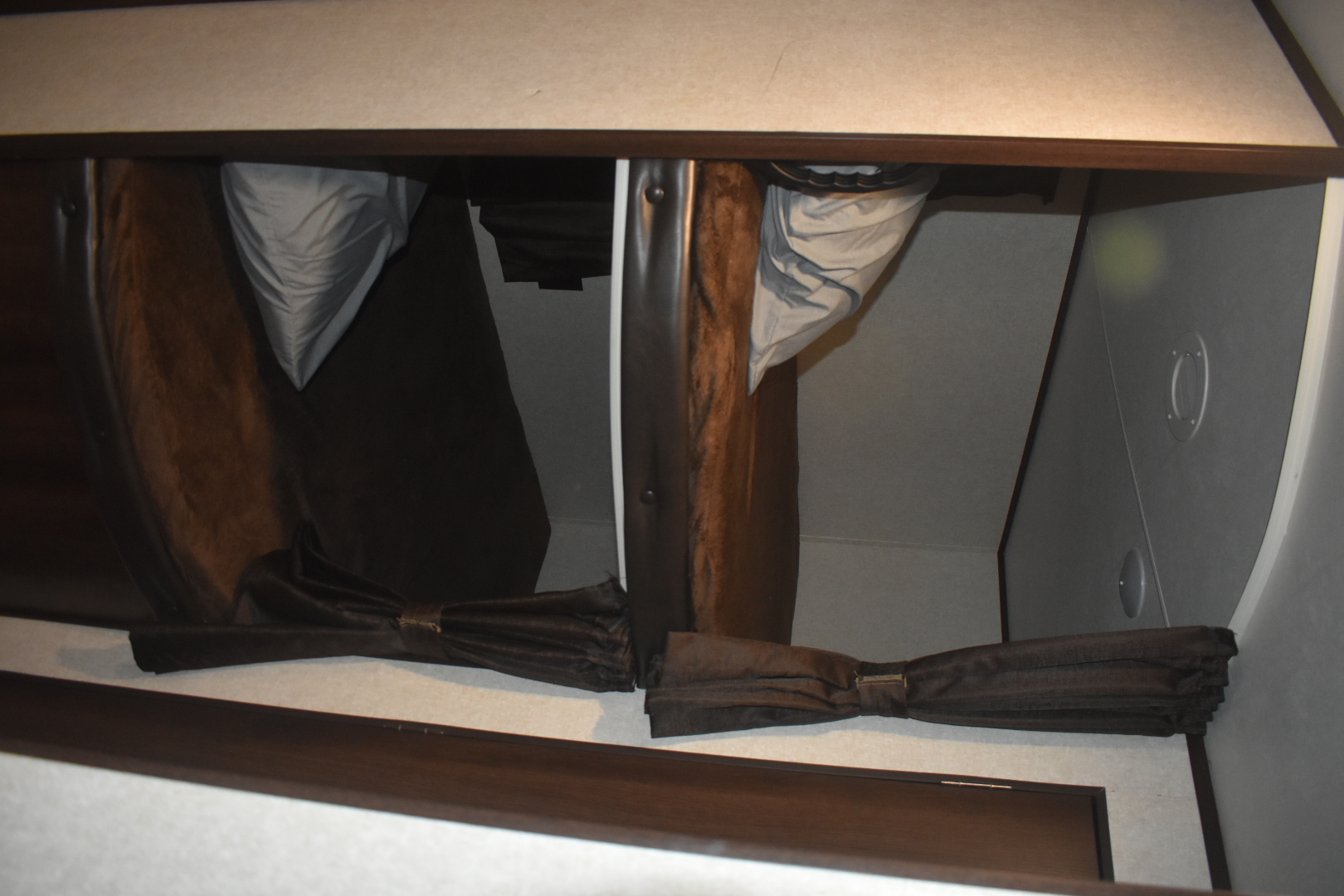 Inside an RV rental, two bunk beds with pulled-back brown privacy curtains and light bedding offer compact sleeping space.. Jayco Jay Flight SLX Rocky Mtn Edition 2019