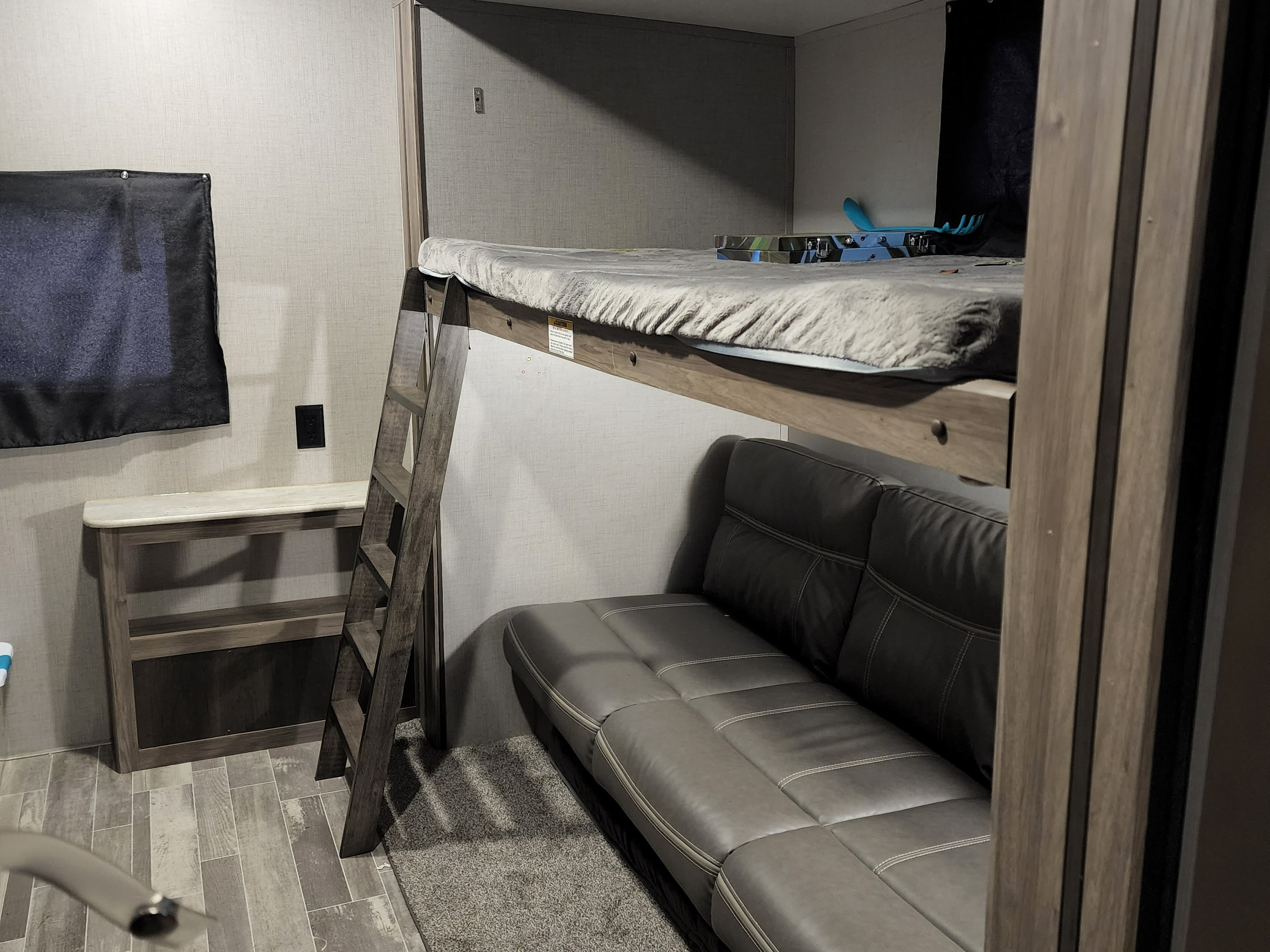 Cozy RV rental bunk area: a ladder leads to the upper bunk bed, with a comfy sofa below for compact living.. Keystone RV ZR331BH20 2020