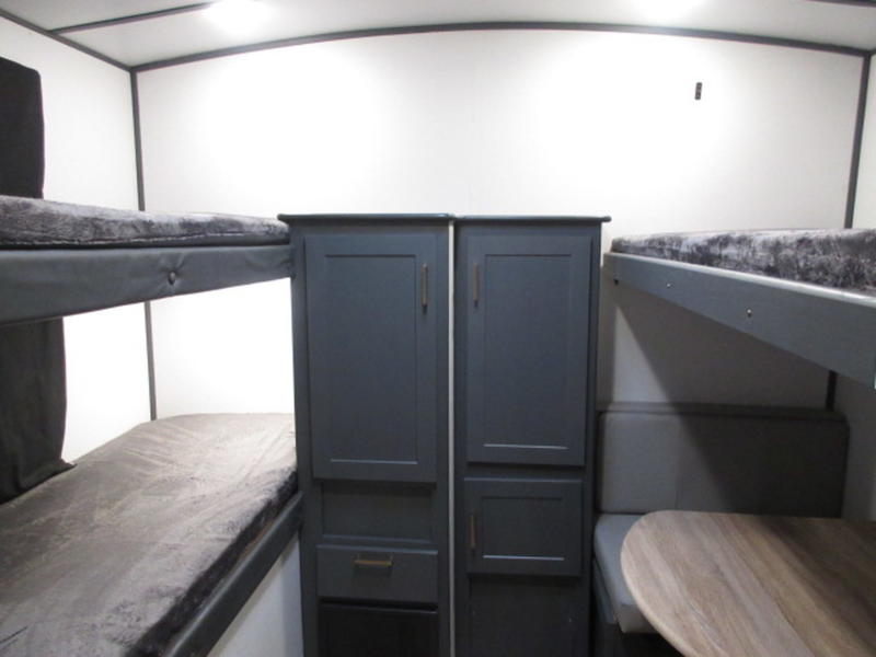 RV rental: A compact travel trailer interior featuring bunk beds, central storage cabinets, and a side dinette.. Keystone RV Bullet Ultra Lite 2022