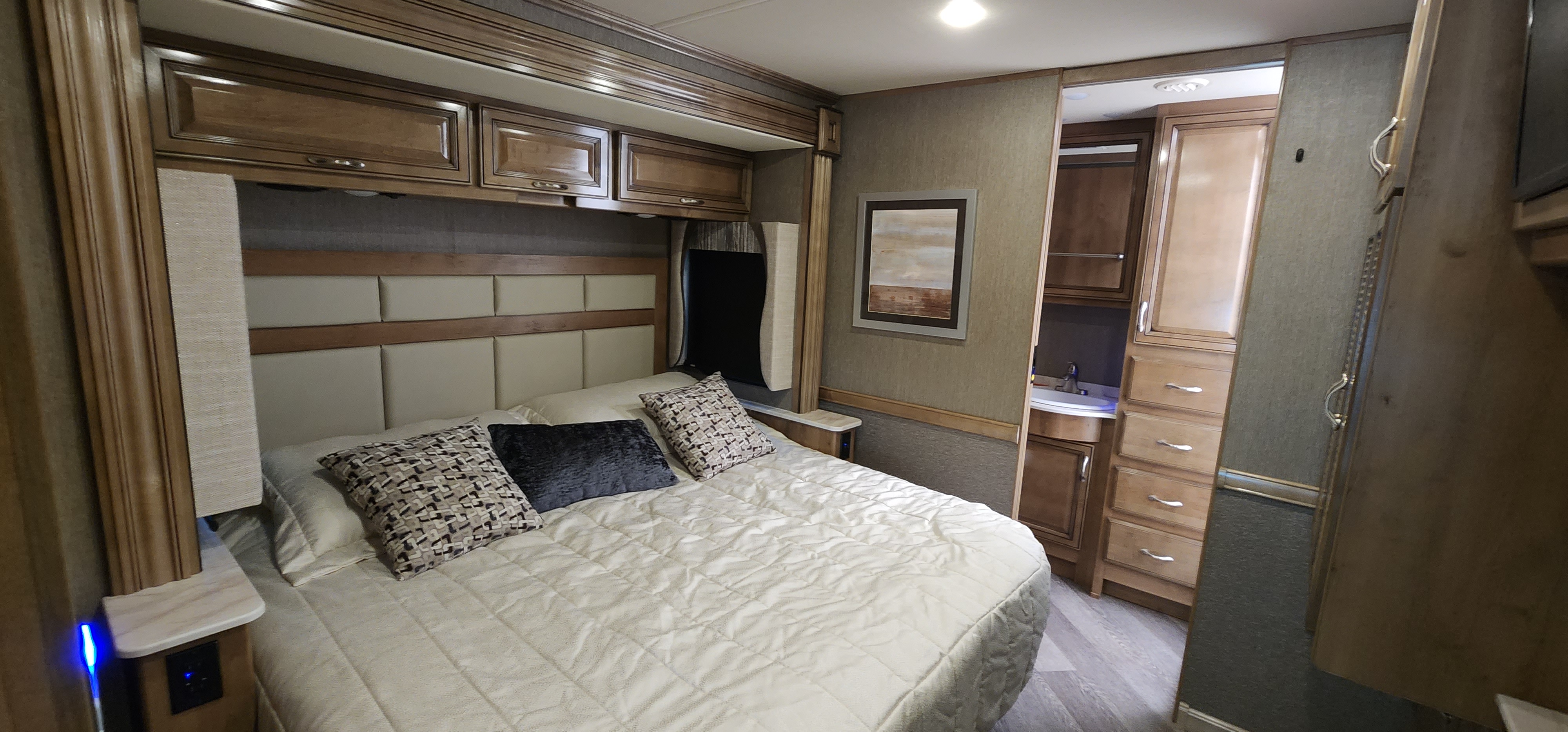 Cozy RV rental bedroom with modern decor, built-in storage, and en-suite sink for comfortable travel.. Bounder Bounder Motorhome 2021