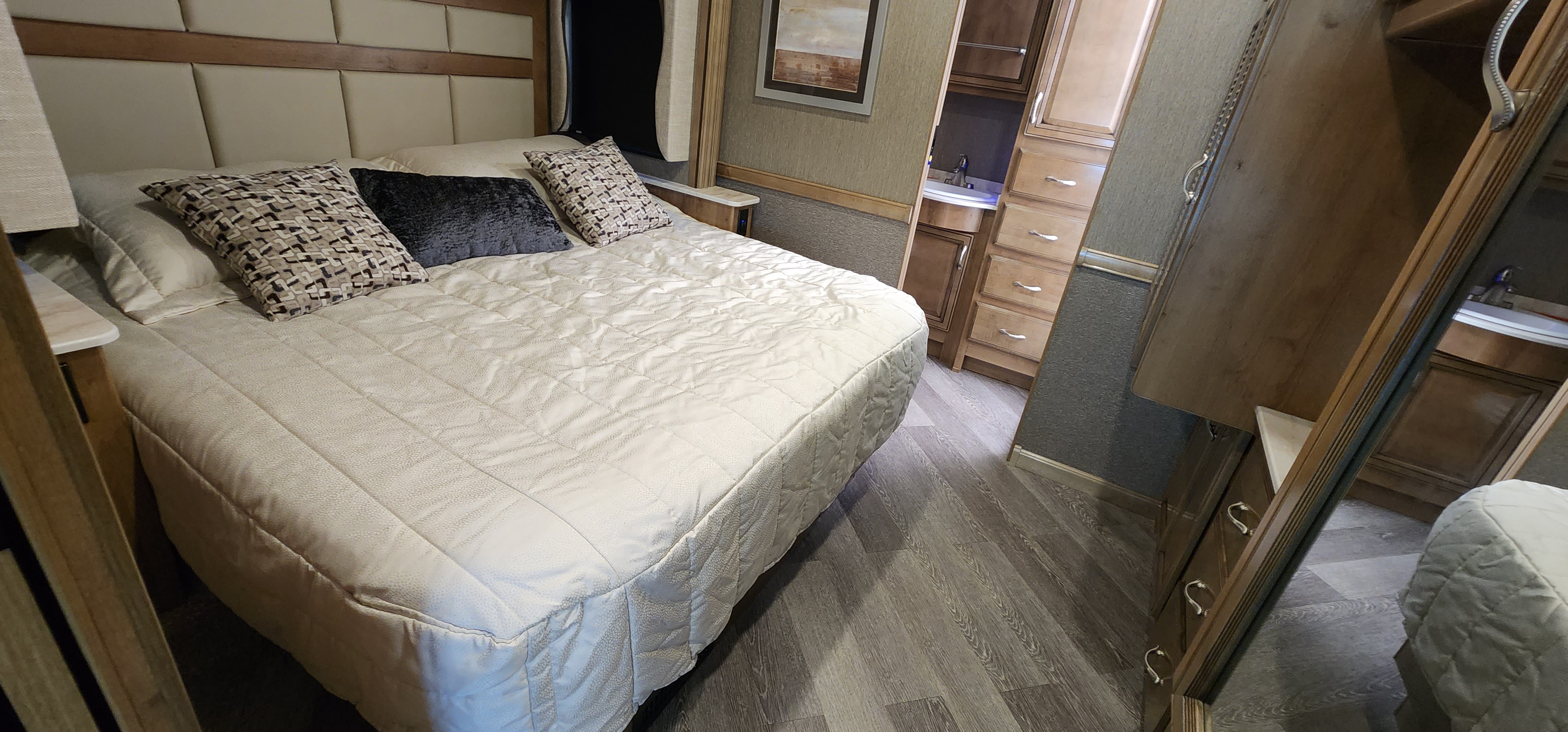 Cozy RV rental bedroom showcasing a comfortable bed, padded headboard, and compact vanity with sink for efficient living.. Bounder Bounder Motorhome 2021