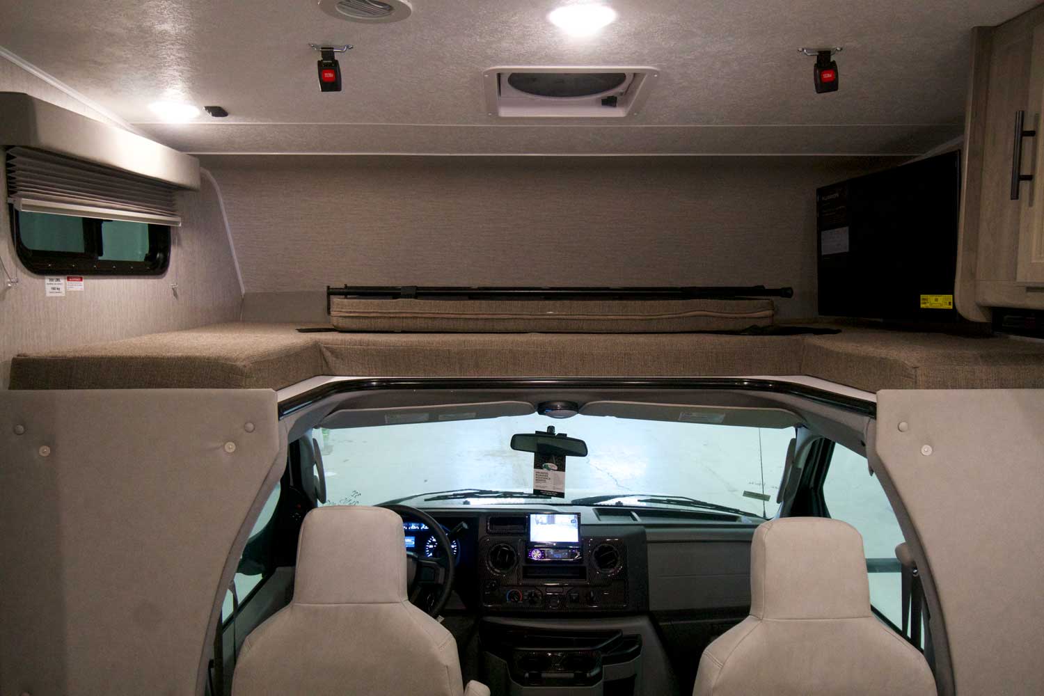 Spacious RV rental interior: over-cab bed, front cockpit, TV, and ceiling vents visible. Ready for your trip!. Coachmen Freelander 2023