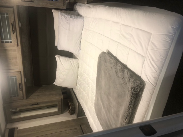 Comfortable RV rental bedroom with clean white bed, gray blanket, and built-in wood cabinetry.. Forest River Salem Hemisphere 2020