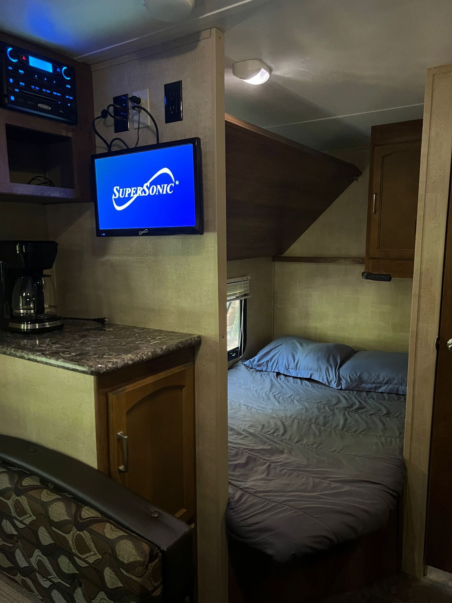 Inside this RV rental, find a compact kitchen/living area with TV and stereo, leading to a cozy bedroom.. Keystone RV Springdale 2014