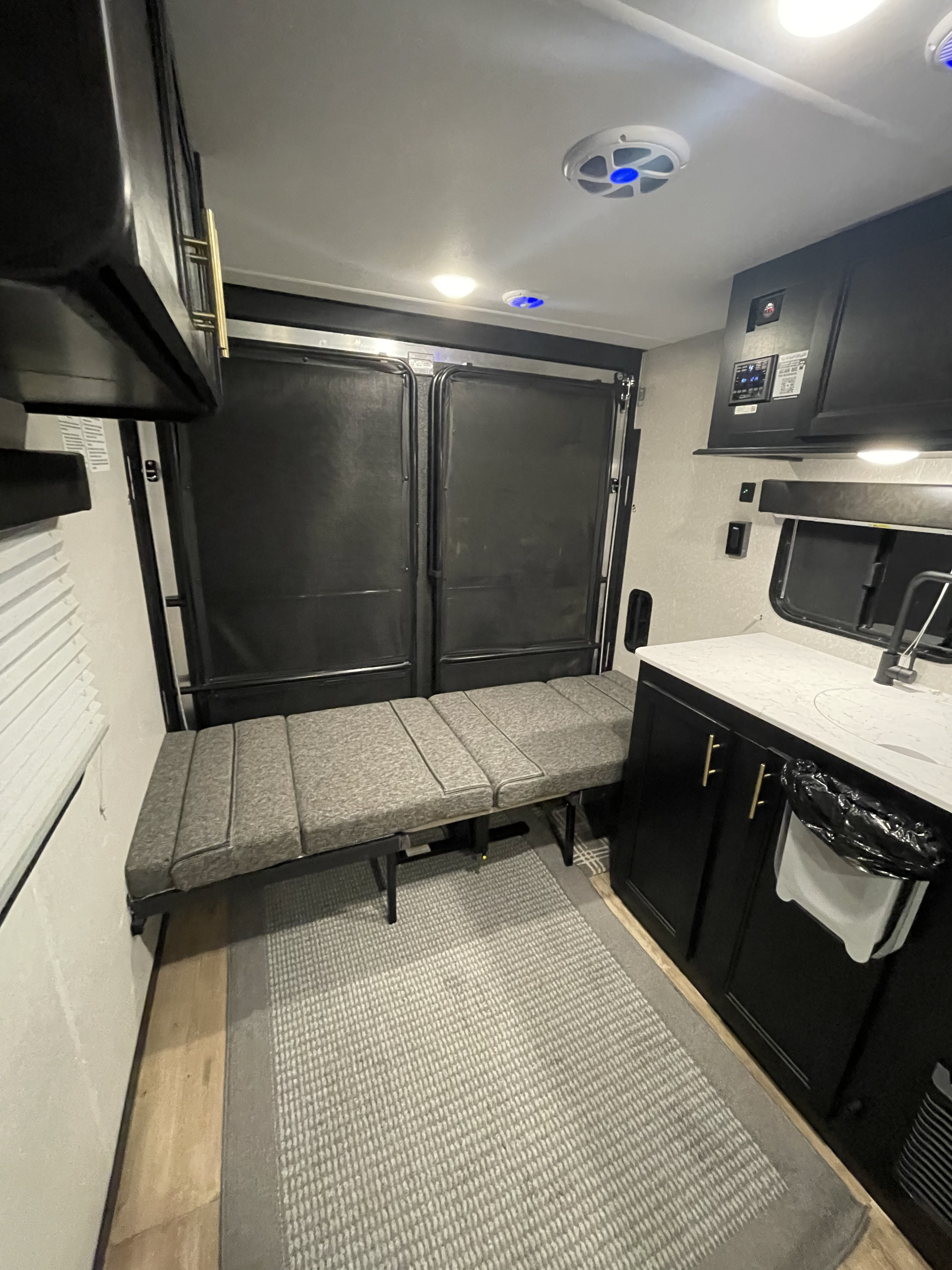 Spacious RV rental interior, featuring a convertible bed/sofa, kitchen, and rear toy hauler door.. Forest River Cherokee Wolf Pup 2022