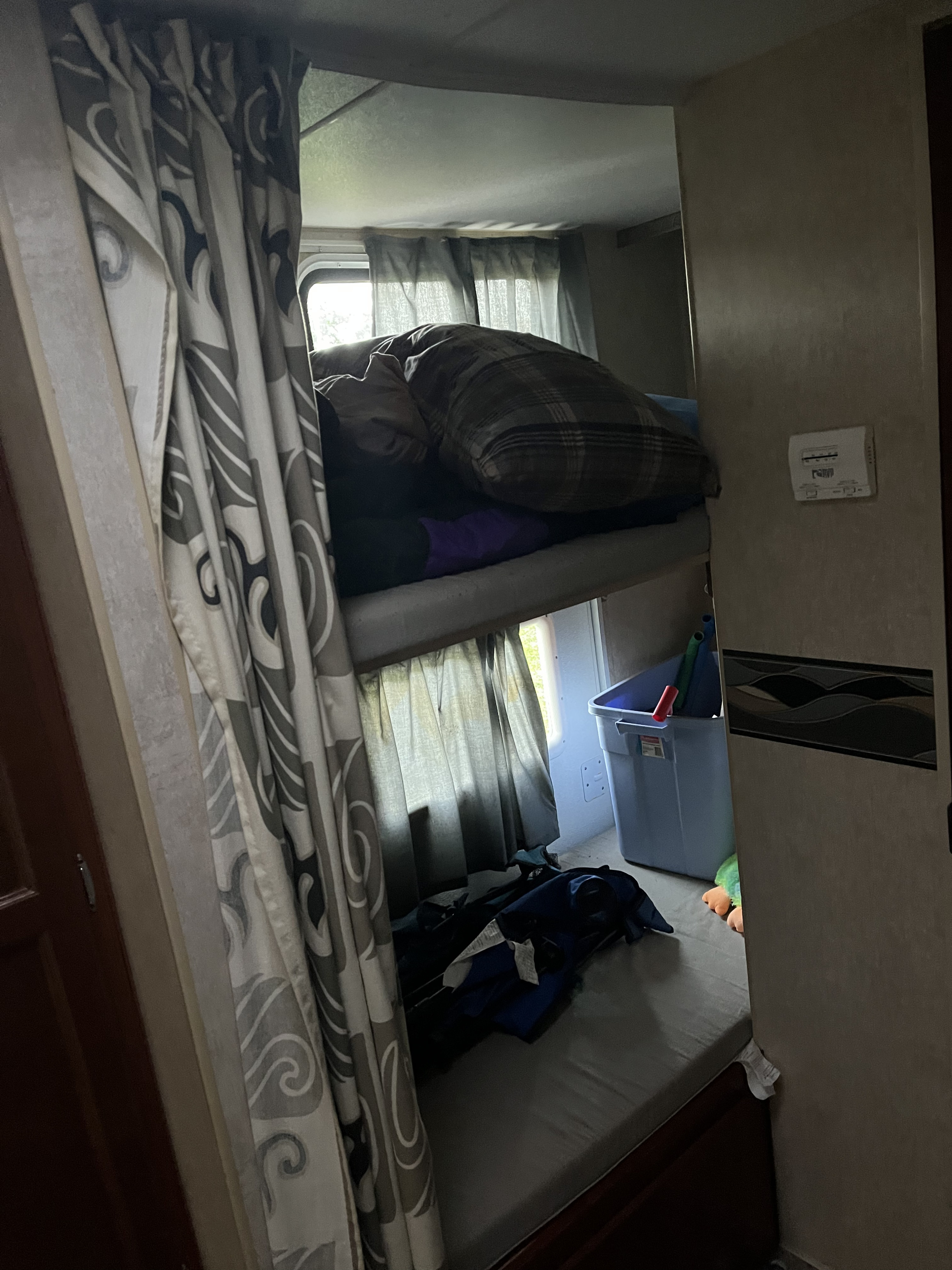 Inside an RV rental: cozy bunk beds with patterned curtains, a sleeping person, and storage for a comfortable stay.. Pioneer Pioneer Trailer 2009