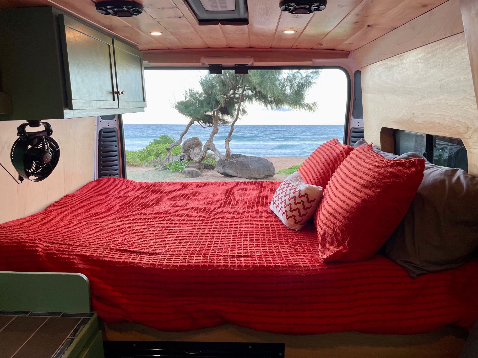 Inside an RV rental, a comfy bed faces a tranquil beach and ocean view.. Dodge Ram Promaster 1500 2021
