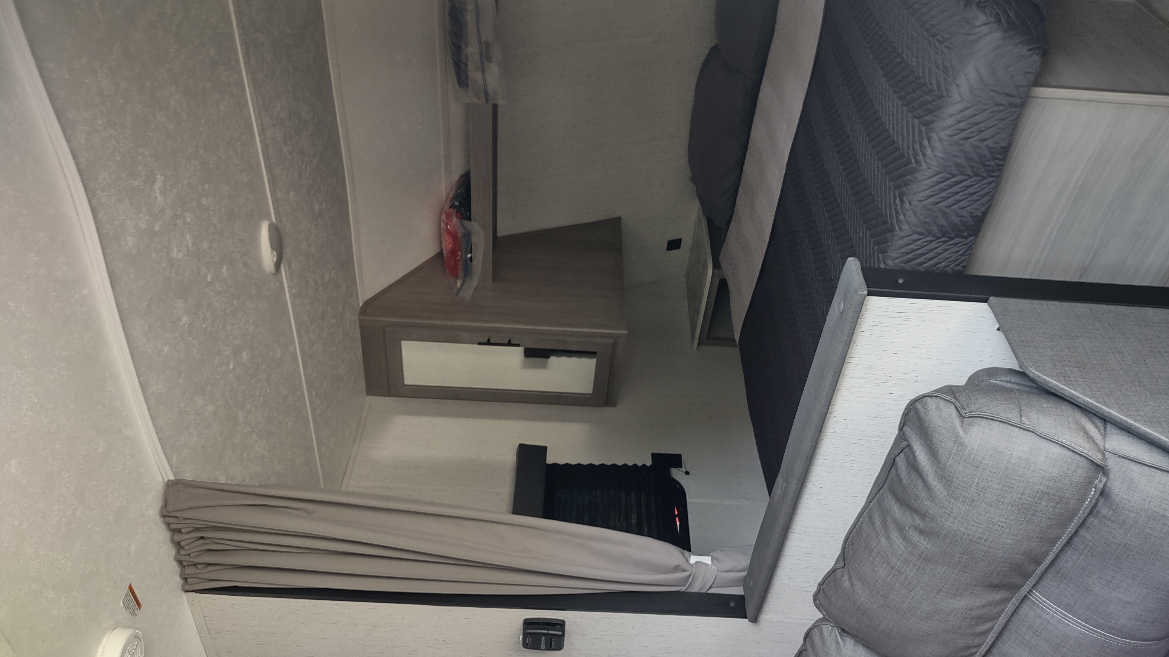 Inside an RV rental: A compact, modern bedroom area with a bed, nightstand, and window blinds, designed for efficient use of space.. Dutchmen Coleman Lantern LT 2022