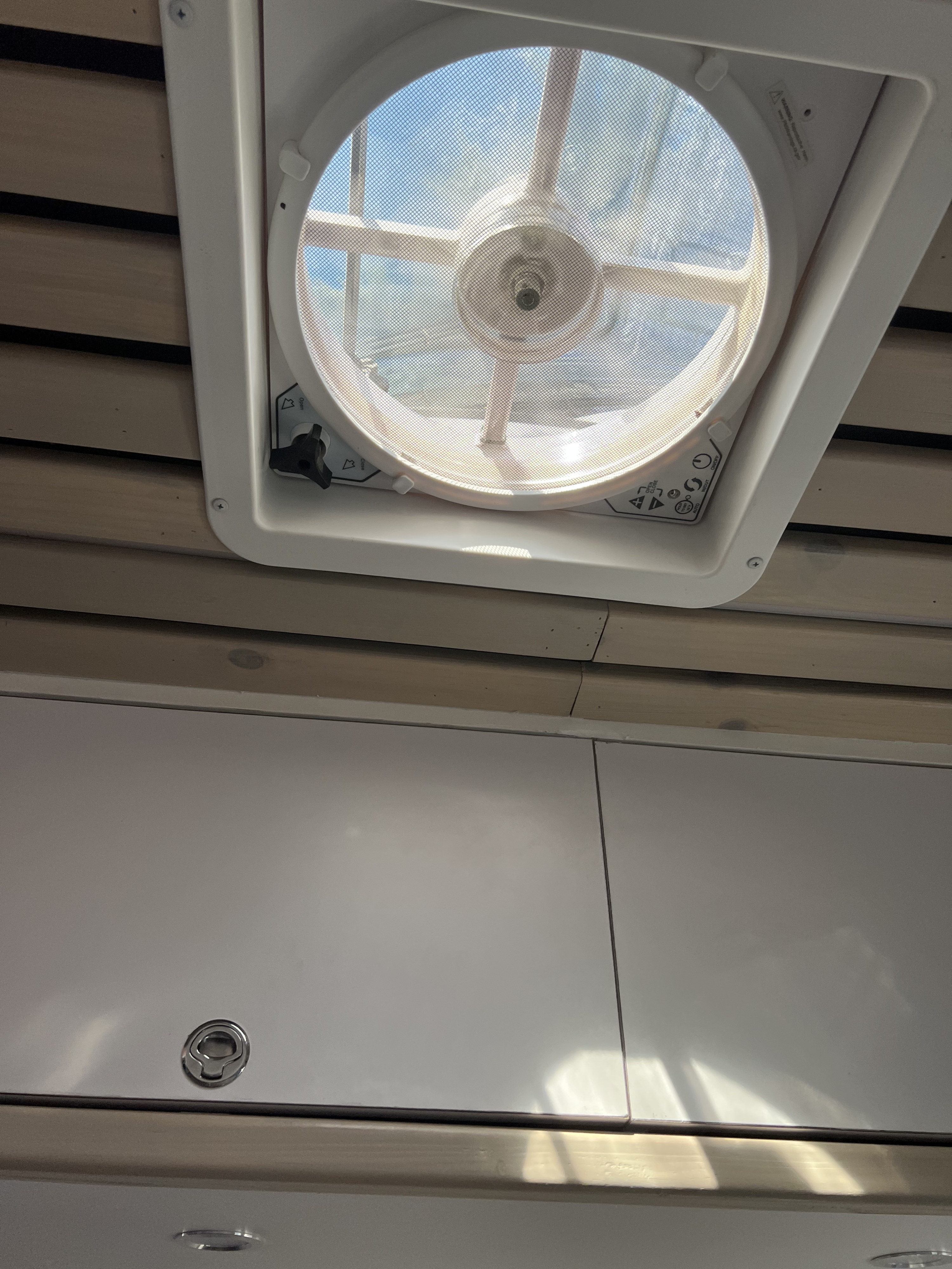 RV rental interior featuring a ceiling fan with a mesh screen, and white overhead cabinets with wooden paneling.. Mercedes-Benz Sprinter 2021