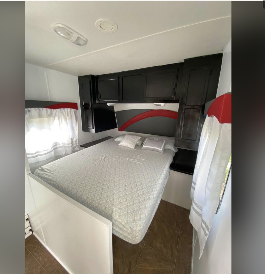 RV rental bedroom: a clean, bright space with a large bed, sleek black cabinets, and red accents.. Jayco Jay Flight 2011