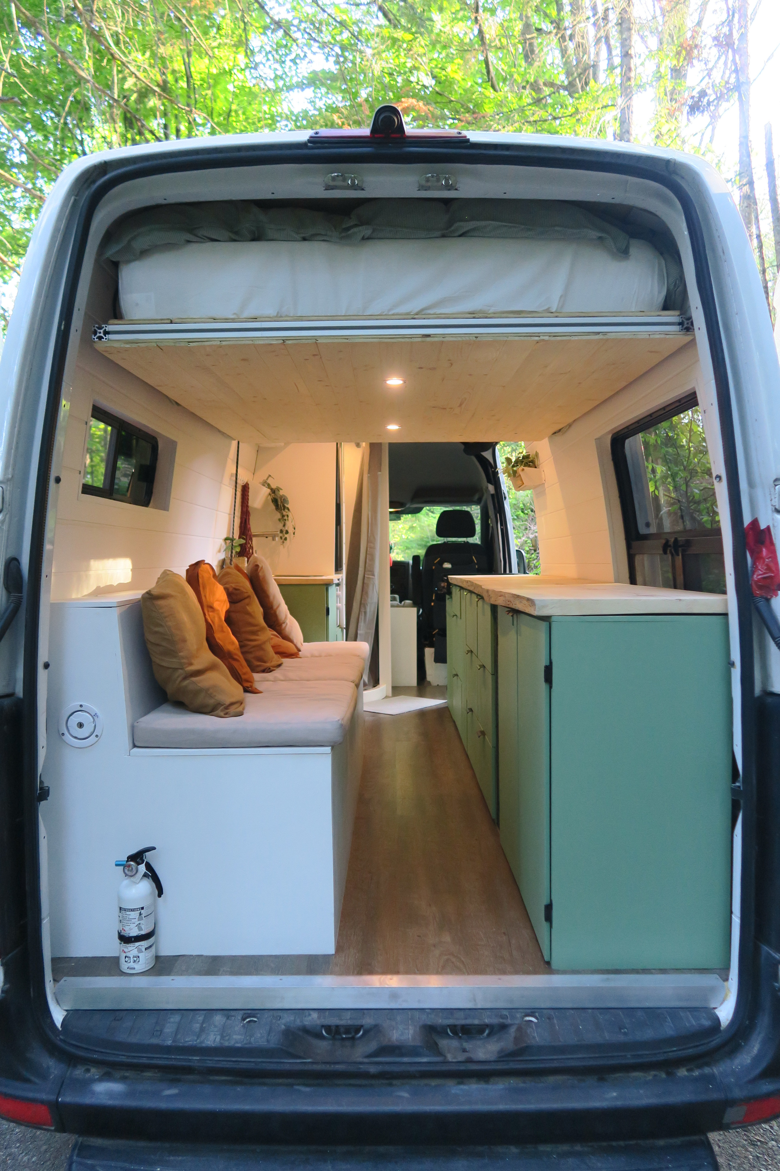 Spacious RV rental interior: custom campervan with a raised bed, cozy bench, and sleek kitchen area. Ideal for travel.. Other Sprinter 2016