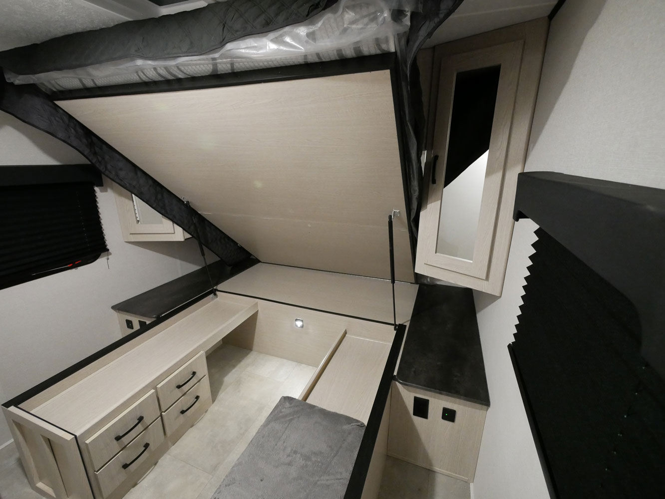 An RV rental bedroom with a lifted Murphy bed, revealing a light wood desk, drawers, and mirrored cabinet.. Forest River Coachmen Apex Ultra-Lite 256BHS 2022
