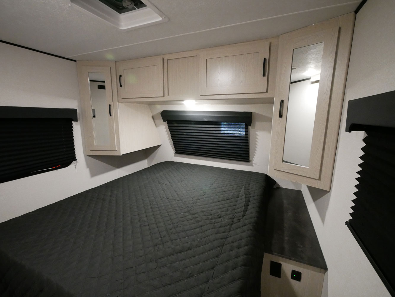 Inside an RV rental, this compact bedroom features a quilted bed, overhead storage, and mirrored cabinets for comfort.. Forest River Coachmen Apex Ultra-Lite 256BHS 2022