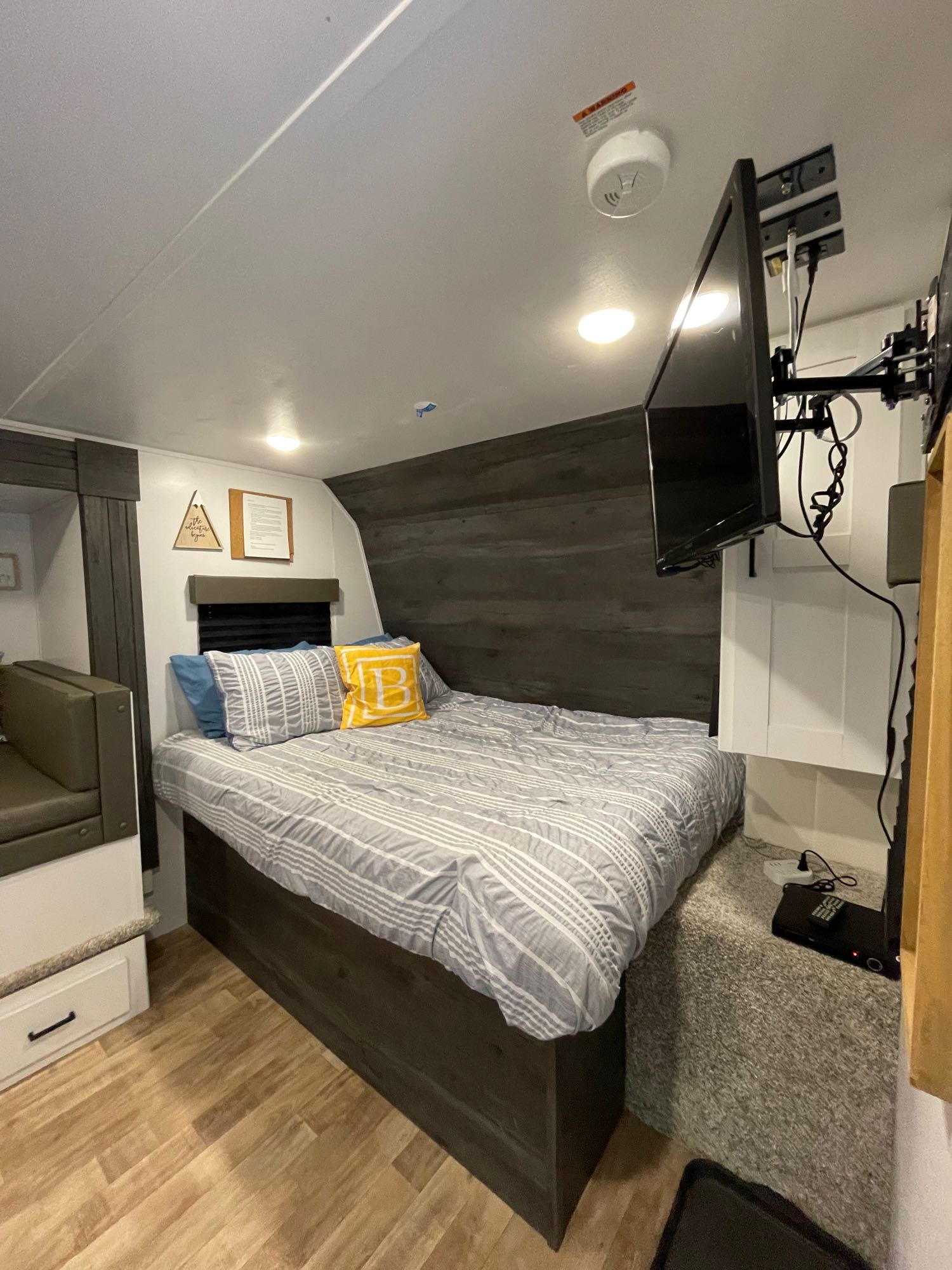 Explore this modern RV rental bedroom featuring a comfy bed, wall-mounted TV, and cozy dinette.. Keystone RV Hideout 2022