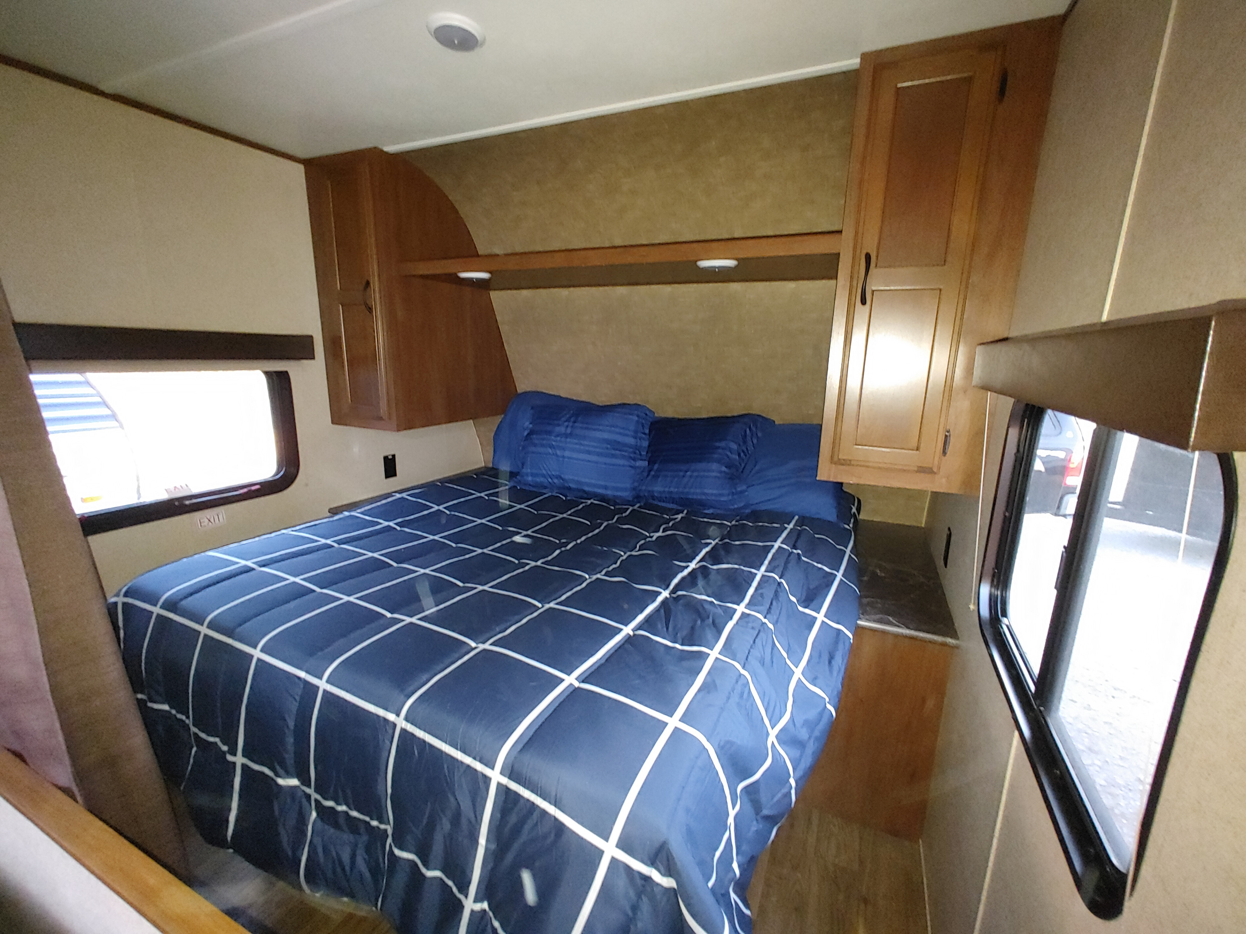 Cozy RV rental bedroom with a comfy bed, overhead cabinets, and bright windows, perfect for travel.. Jayco Jay Flight SLX 2016