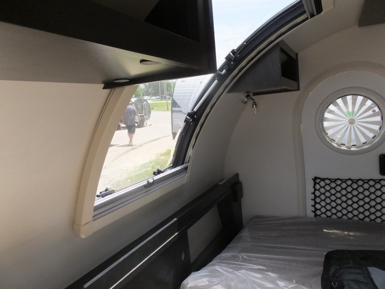 This compact rv rental interior features a comfortable bed, large side window, and distinct circular rear window.. nuCamp T@G XL Boondock 2022