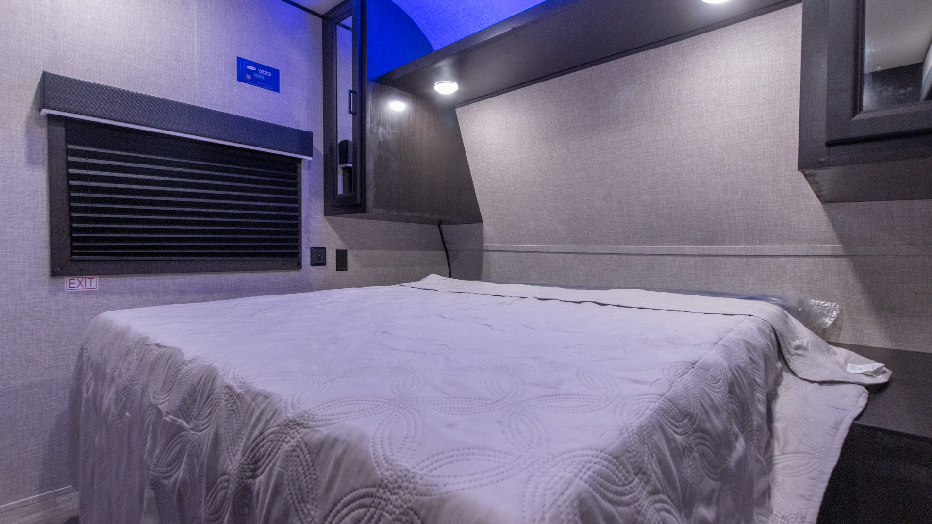 Compact RV rental bedroom featuring a comfy bed, window with shades, built-in storage, and ambient lighting.. Jayco Jay Flight SLX 2022