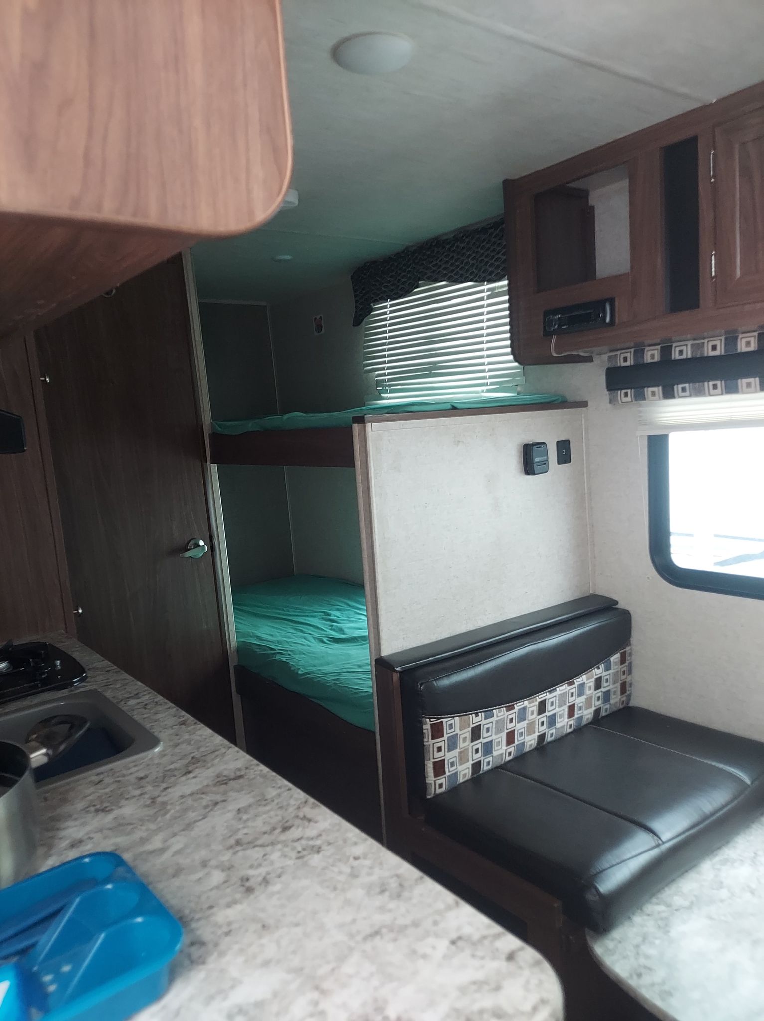 An RV rental interior features a functional kitchenette, comfortable dinette seating, and two cozy bunk beds.. Heartland RVs Pioneer 2018