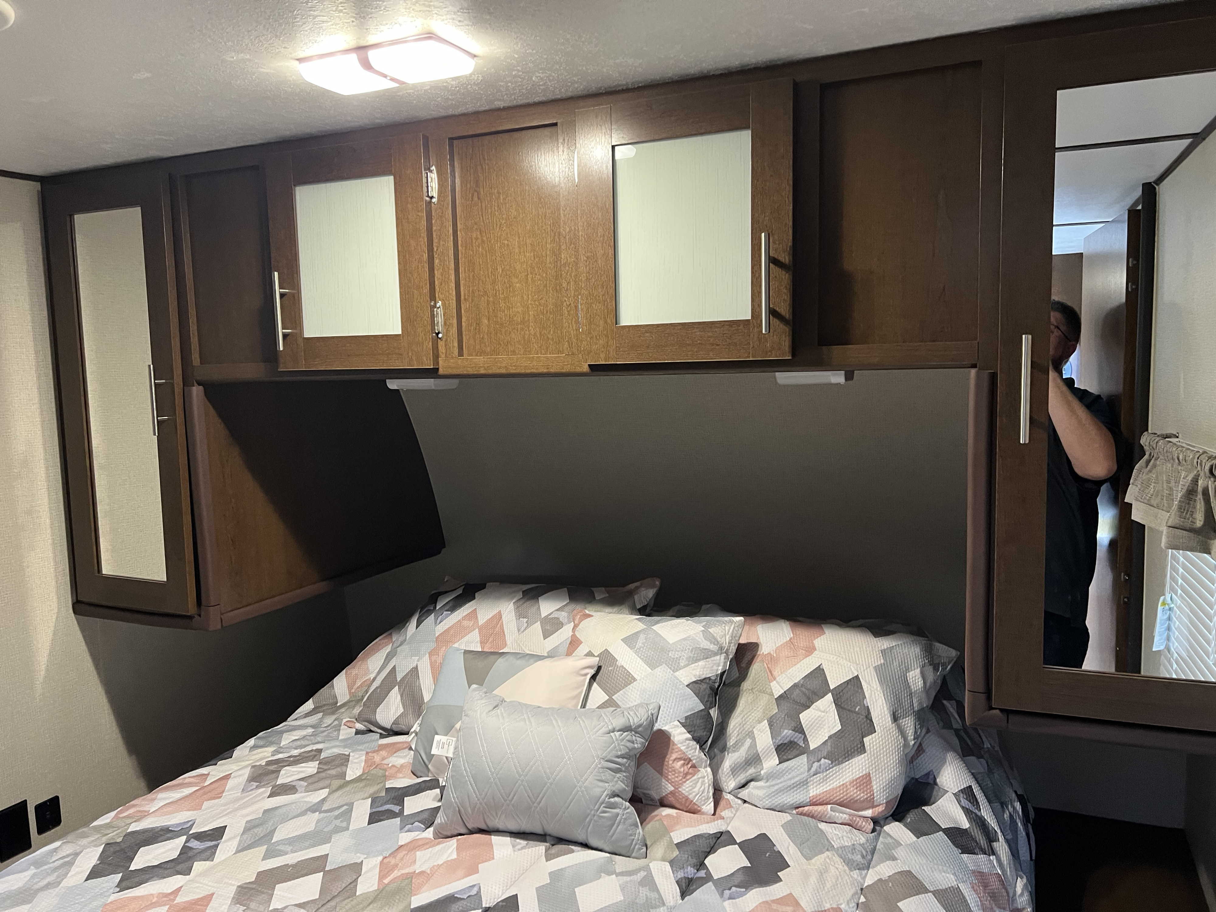 Step into comfort in this RV rental bedroom featuring overhead cabinets, patterned bedding, and compact design.. Avenger 31DBS 2019