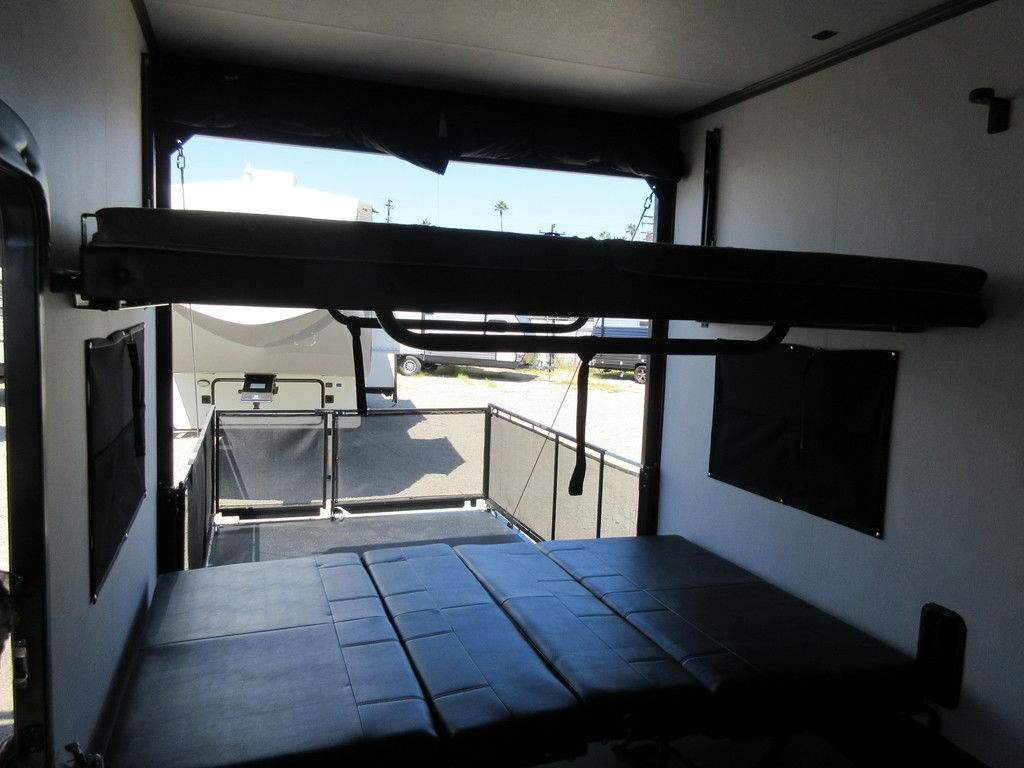 RV rental: Toy hauler's versatile interior with lower beds, an upper bunk, and an open ramp for easy access.. Forest River Vengeance 2022