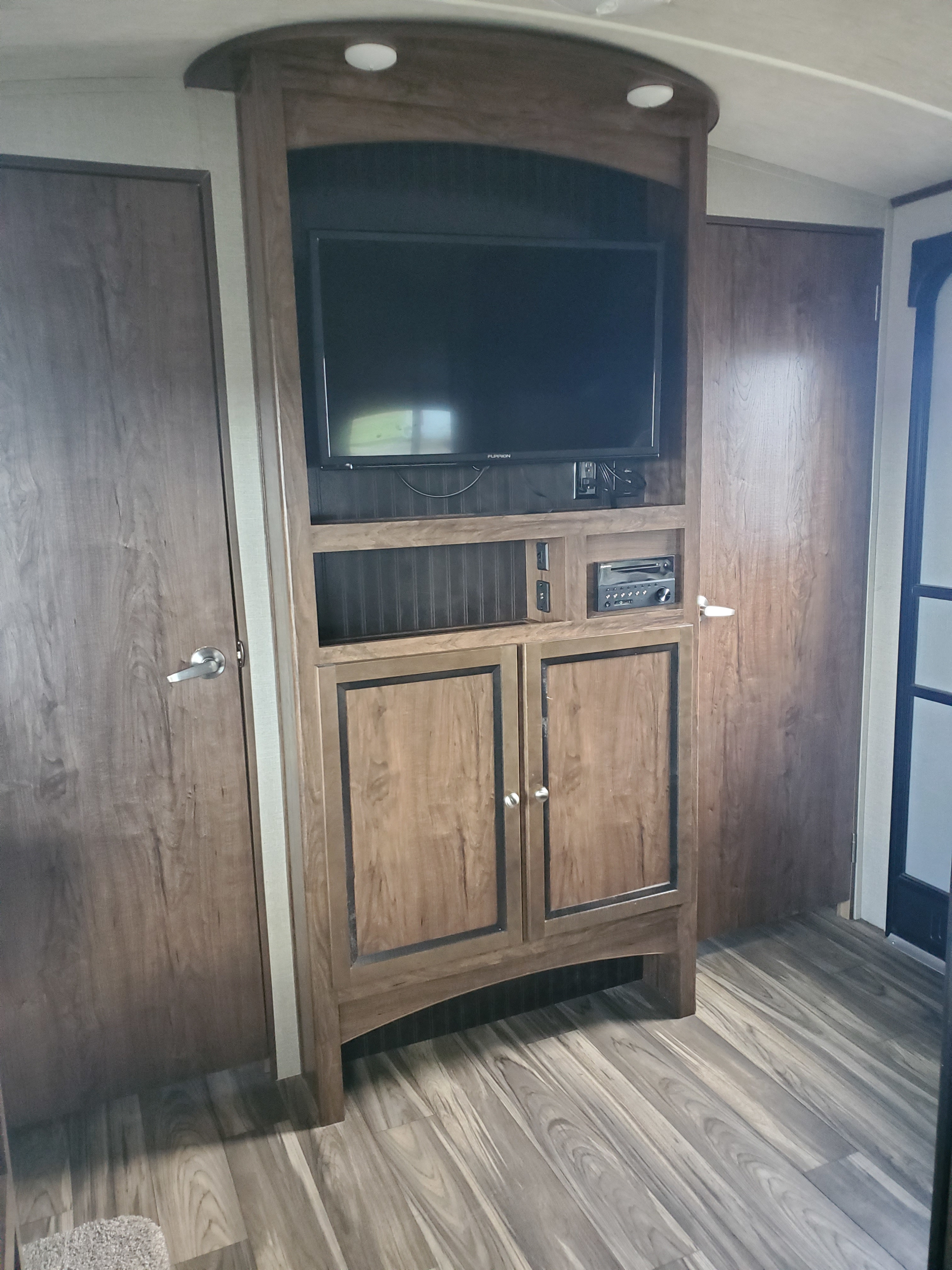 Modern RV rental interior with a wood entertainment center, TV, stereo, storage cabinets, and laminate flooring.. Cruiser RV MPG Ultra Lite 2018